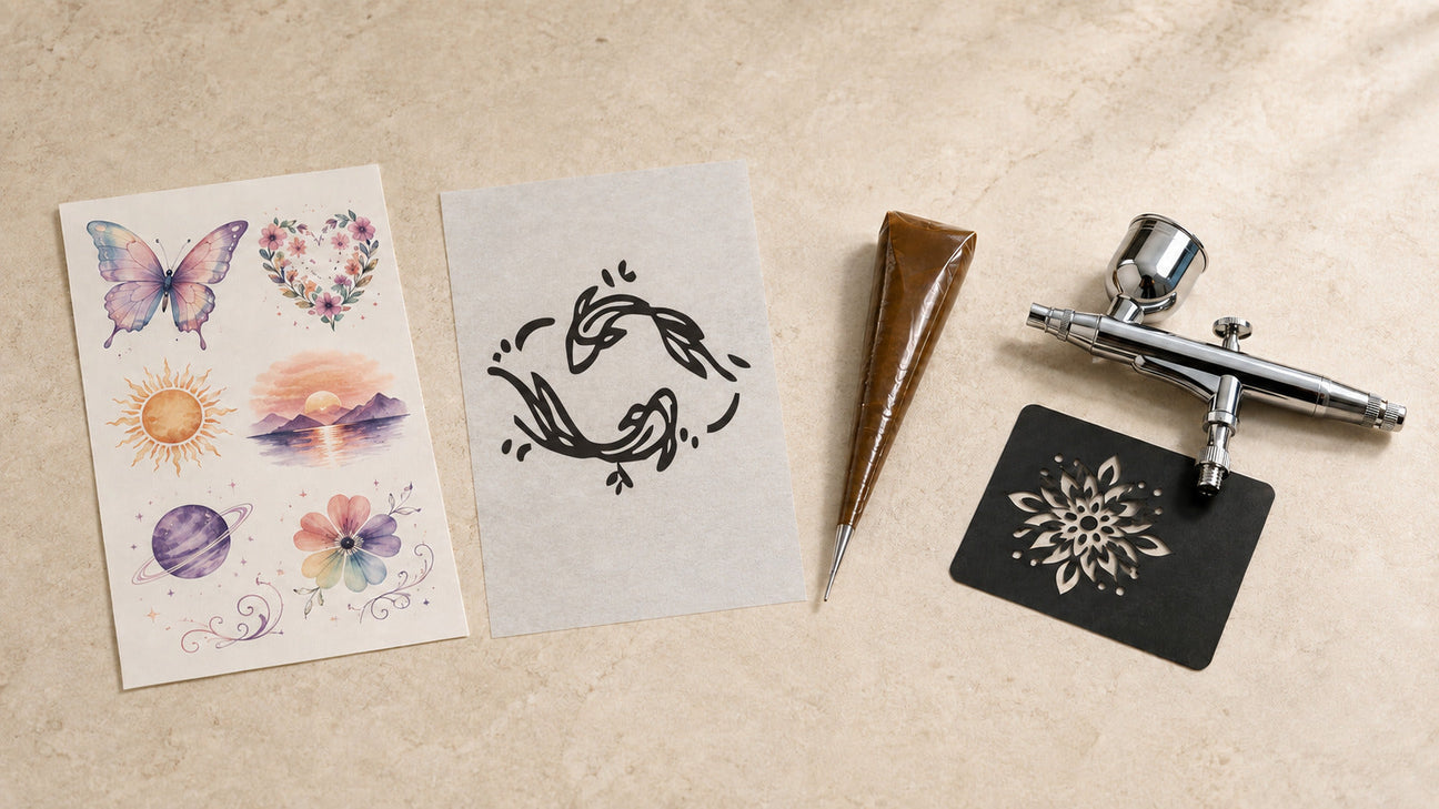 Semi permanent tattoos, water-transfer designs, airbrush tools, and a stencil displayed together on a warm neutral surface.