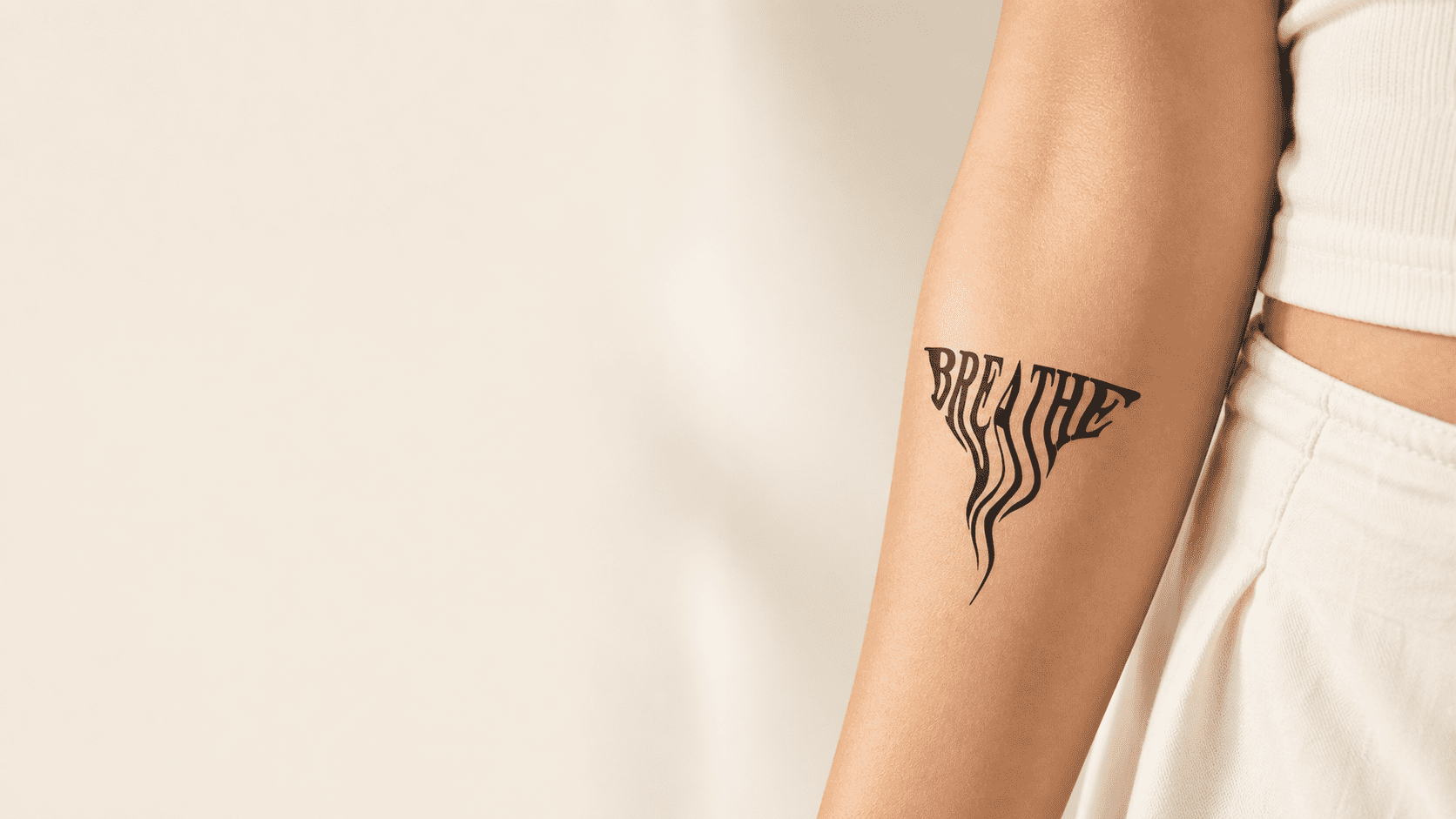 Temporary tattoo featuring the word “BREATHE” in bold warped lettering with flowing drip-like lines on the outer upper arm.