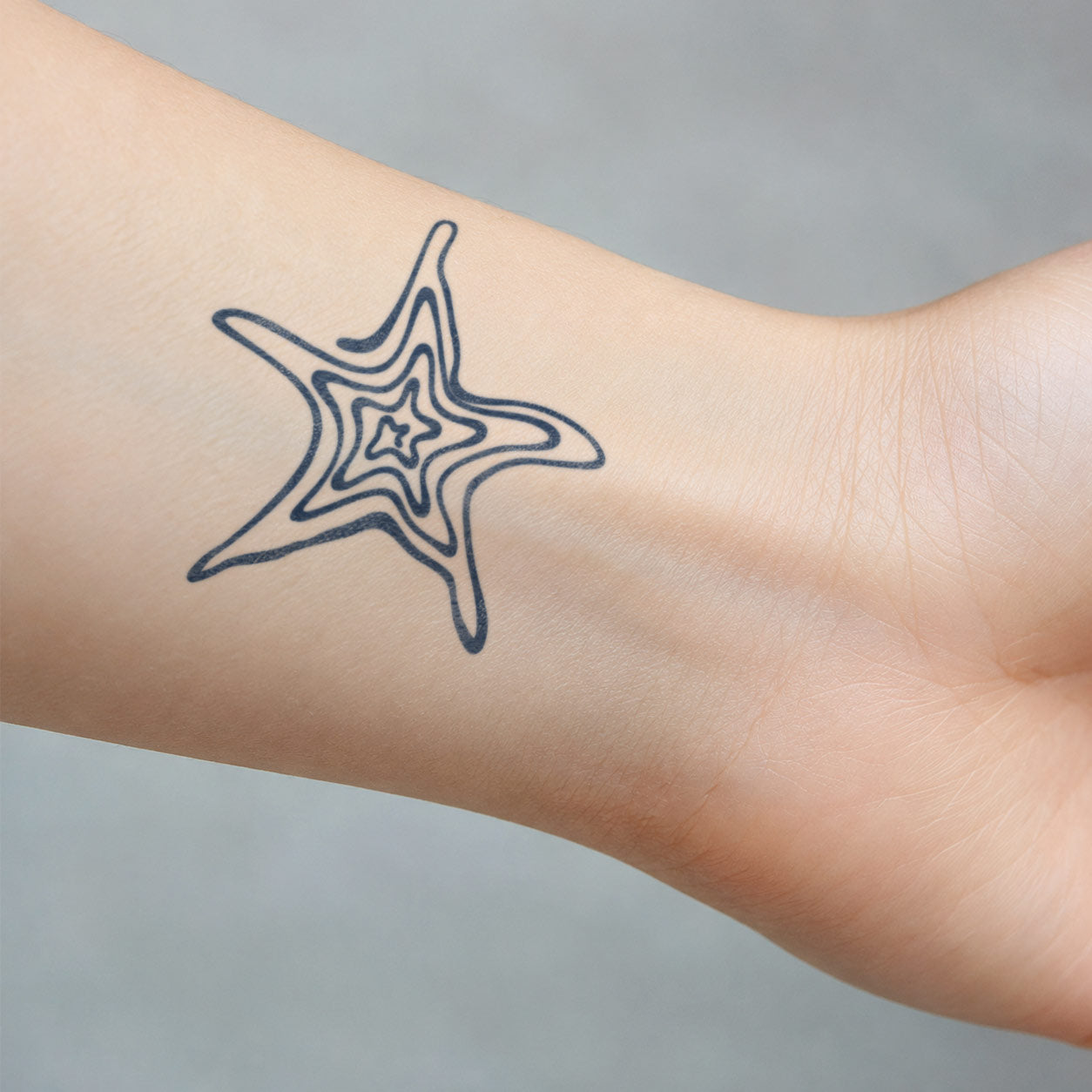 Minimal temporary tattoo featuring a warped, layered five-point star placed along the inner wrist.
