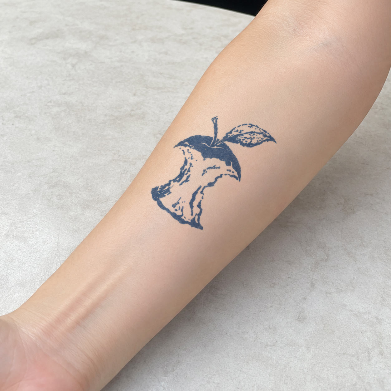 Temporary forearm tattoos featuring an eaten apple core with a stem and leaf.