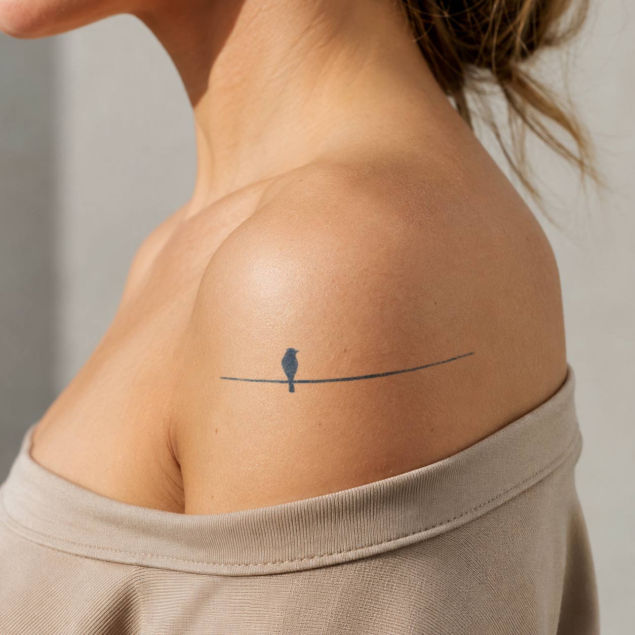 Temporary shoulder tattoos featuring a small bird perched on a single curved wire.
