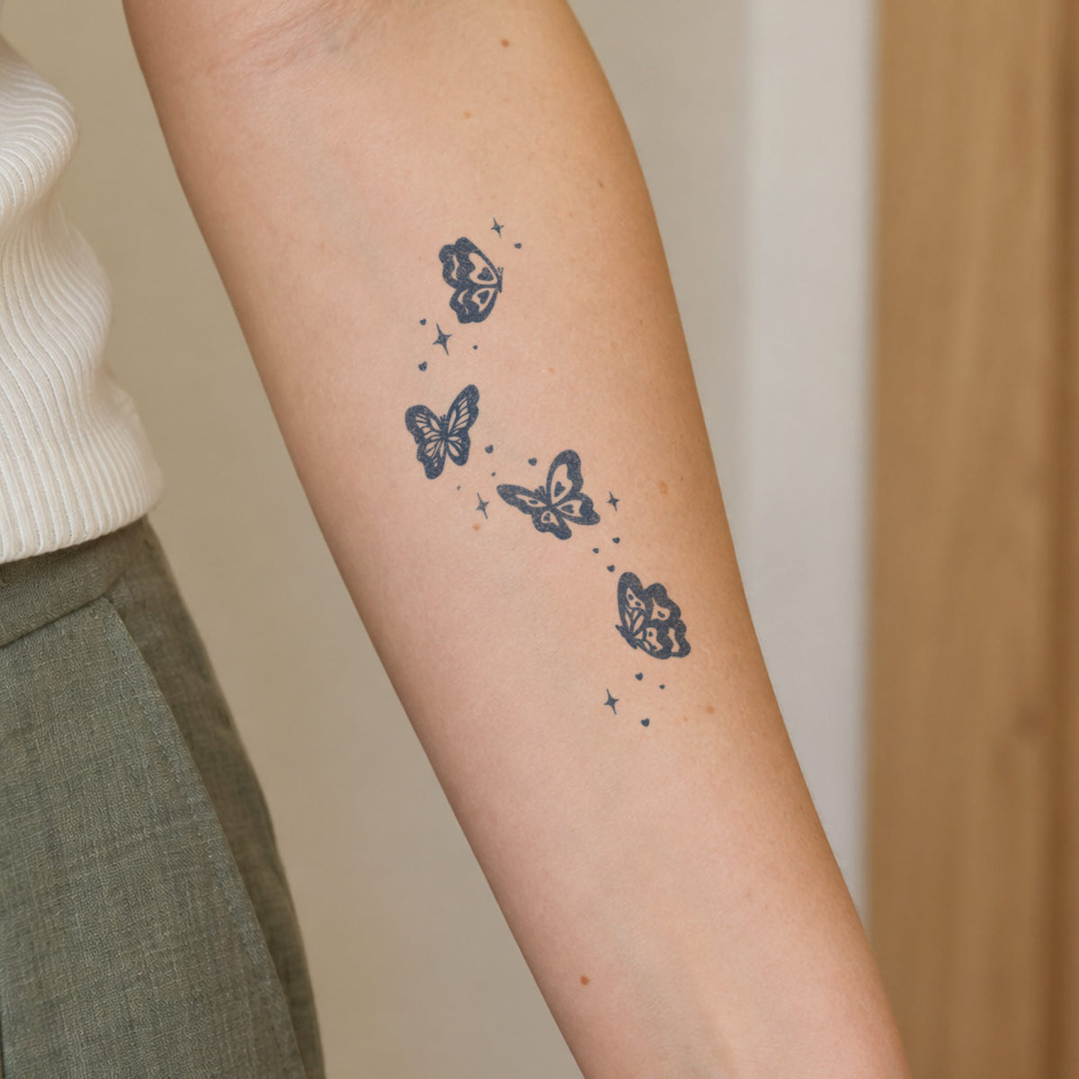Butterfly temporary tattoos featuring four delicate butterflies with small stars and heart details on the inner forearm.
