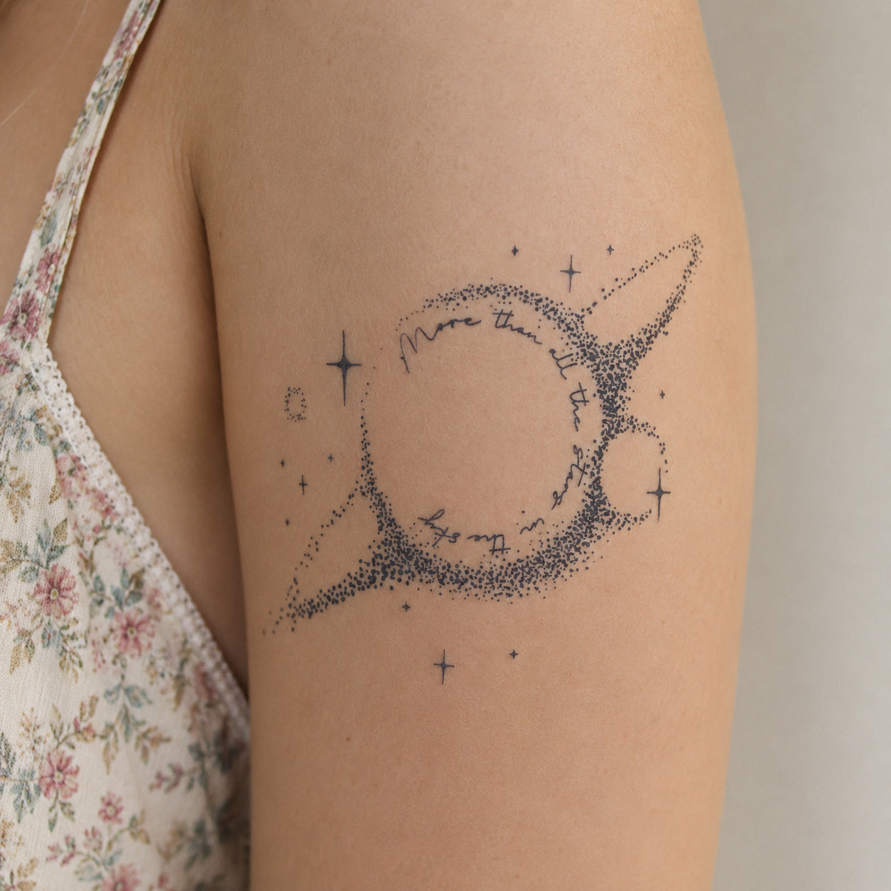 Celestial heart outline tattoo with stars, dots, and handwritten quote details placed on a woman’s upper arm, featuring a delicate constellation temporary tattoo design.