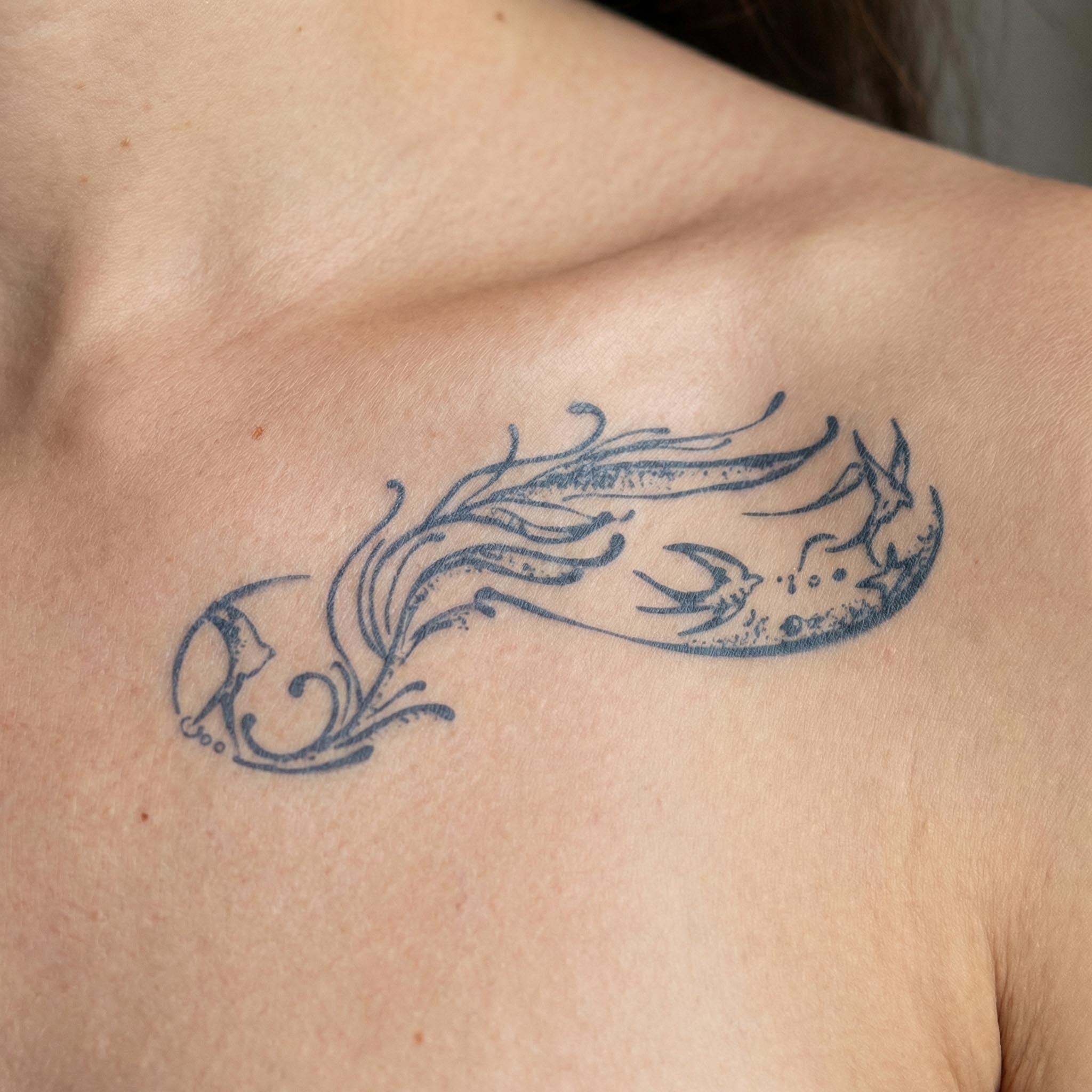 Flowing ocean-inspired temporary tattoo placed along clavicle in fine line style