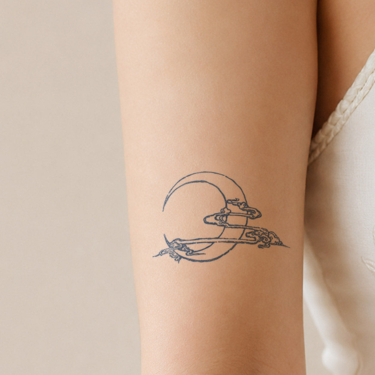 Temporary arm tattoos featuring a crescent moon framed by flowing ornamental clouds on the upper arm.
