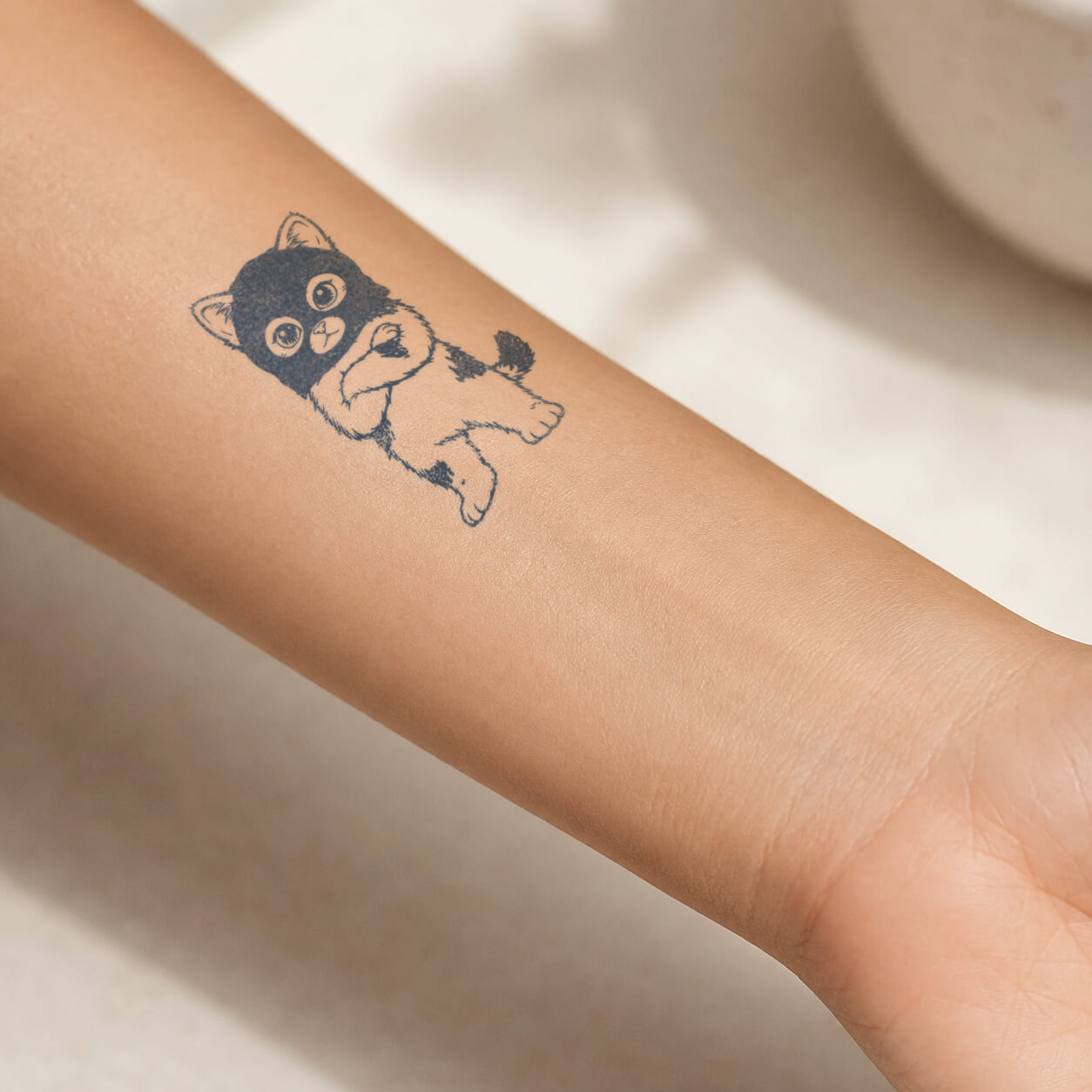 Cute masked kitten design from a collection of cute temporary tattoos, shown on the inner forearm.