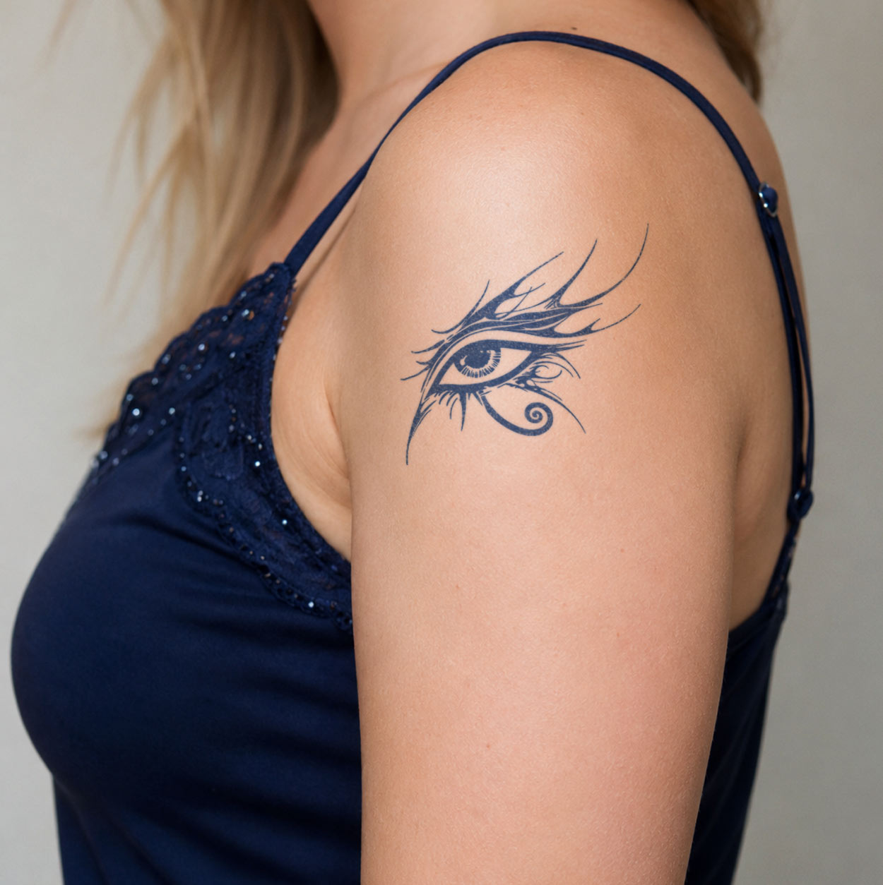 Ancient Egyptian temporary tattoo featuring a detailed Eye of Horus symbol with sweeping lines and a curled lower flourish on the upper arm.