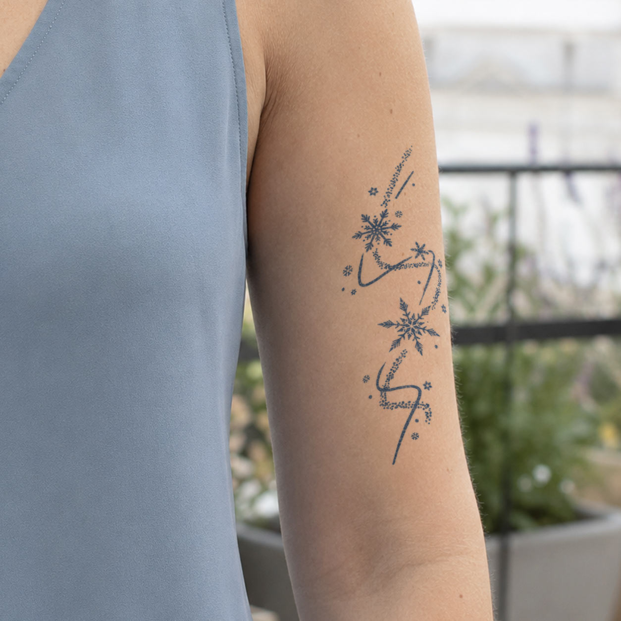 Temporary arm tattoos featuring snowflakes, scattered stars, dotted paths, and flowing falling trails.