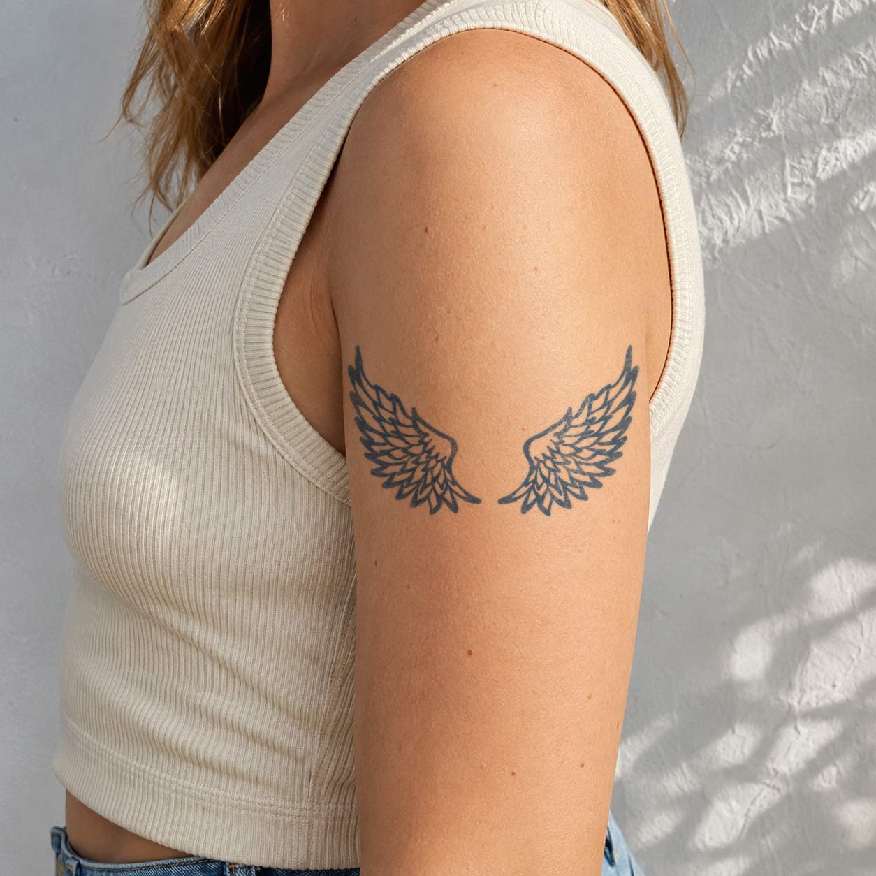 Temporary arm tattoos featuring two outward-facing wings with layered individual feather details.
