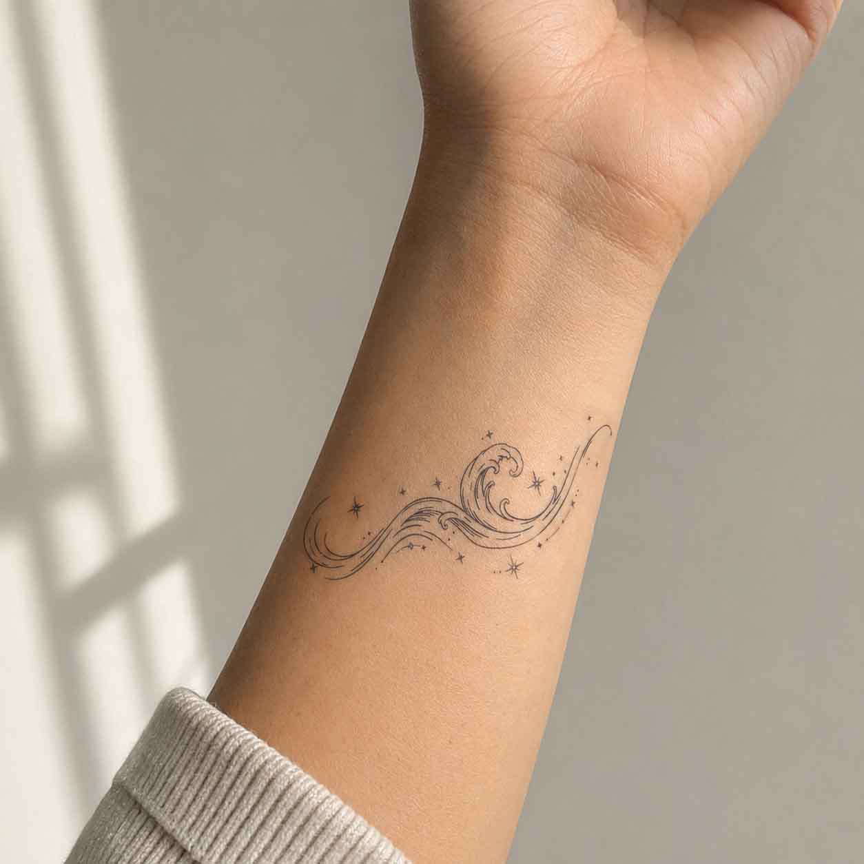 Fine line nature-inspired temp tattoo of a wave and star design applied on the wrist.