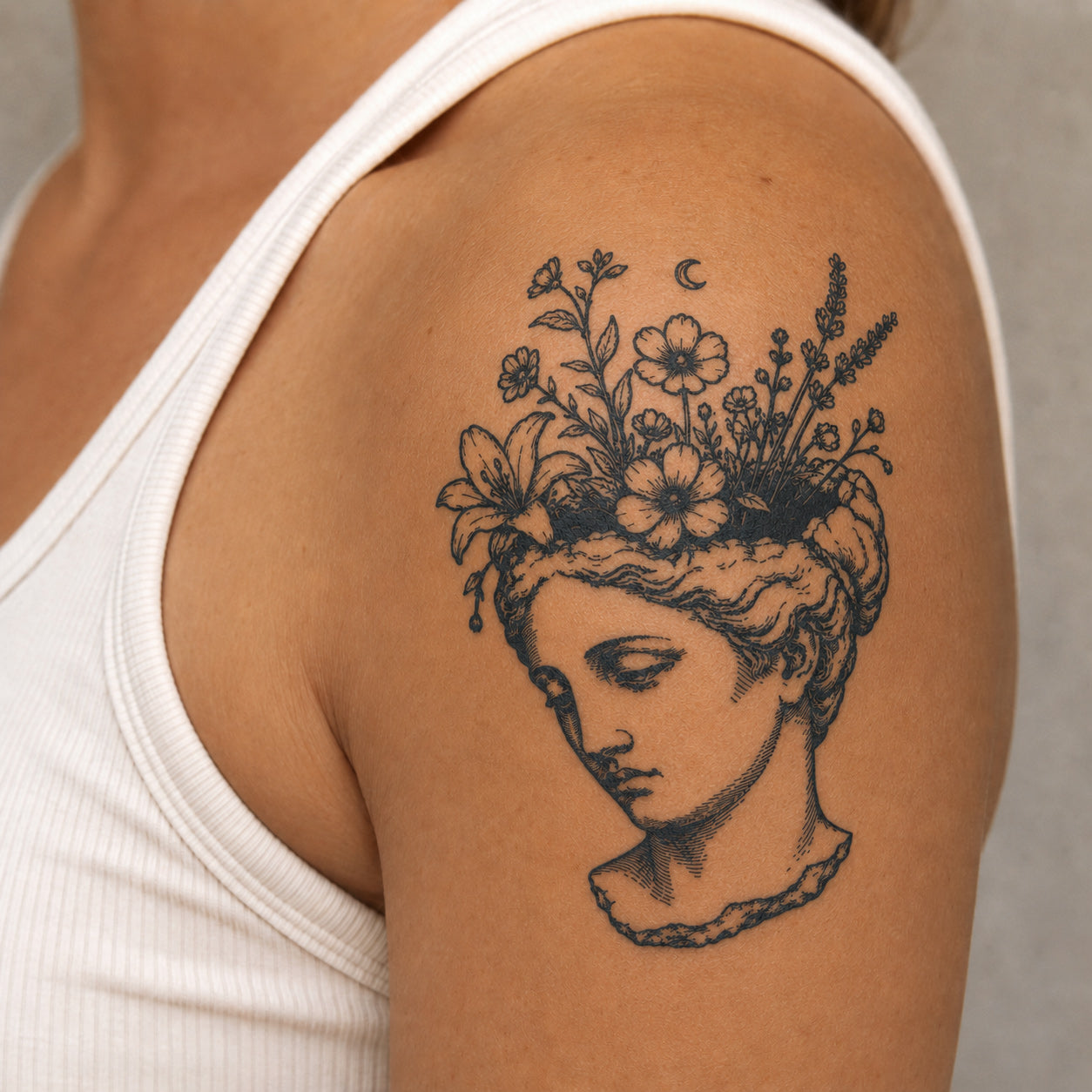 Greek statue inspired floral temporary tattoo with blooming flowers and moon detail on a woman’s upper arm, featuring a delicate floral temporary tattoo design.