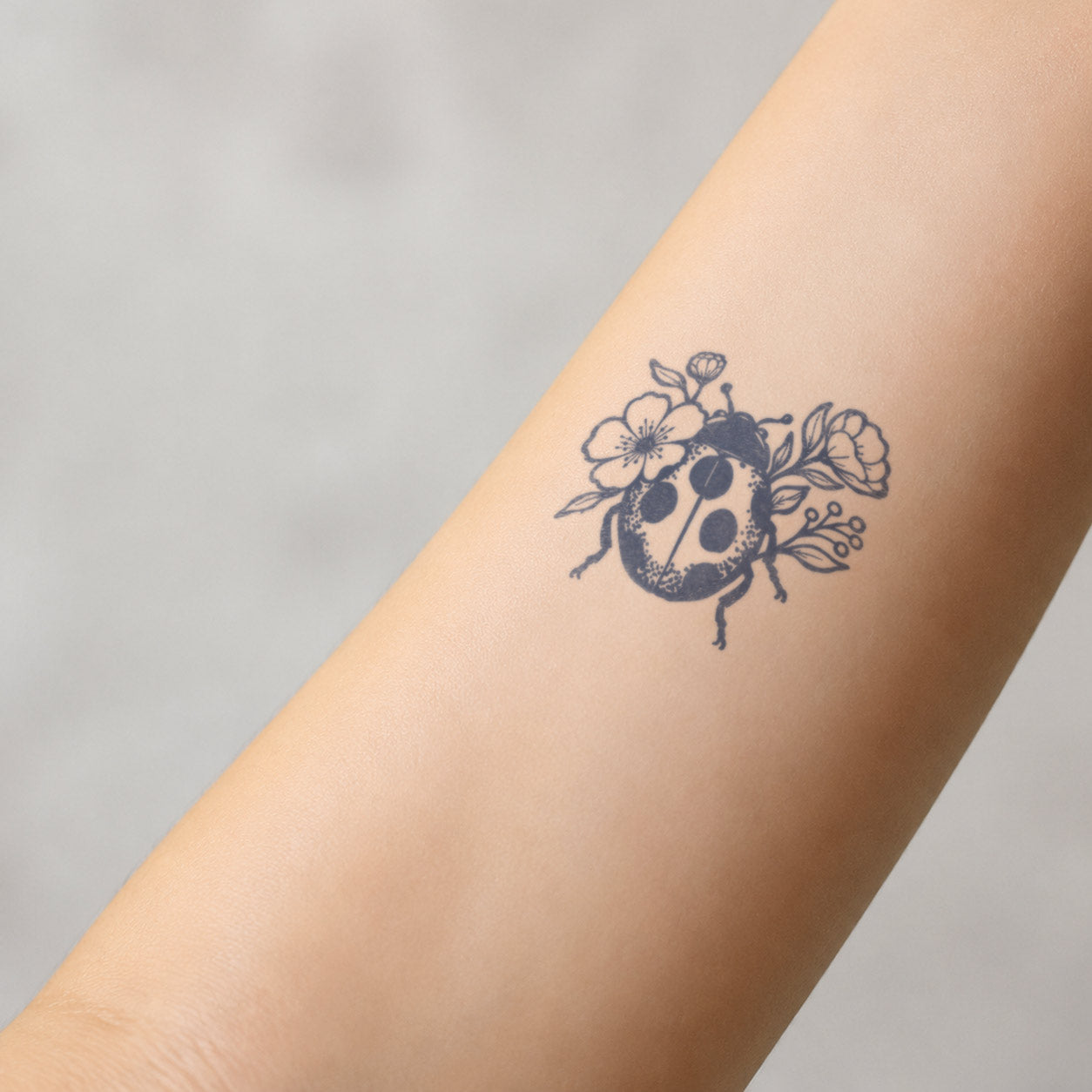 Flower semi-permanent tattoo featuring a detailed ladybug surrounded by blooming flowers and leaves on the forearm.
Floral Bee Temporary Tattoo