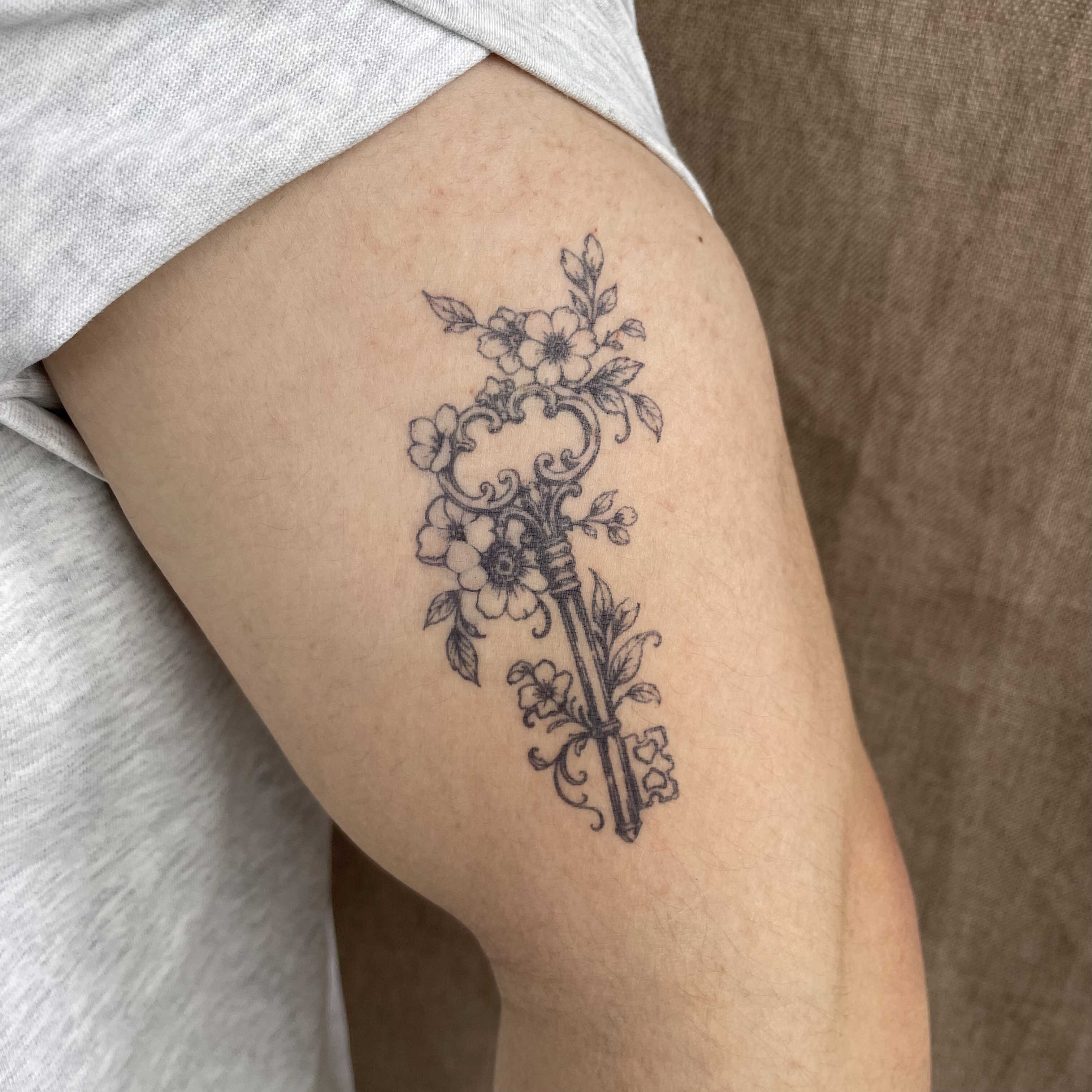 Floral key temporary tattoo with vintage flowers on upper arm 