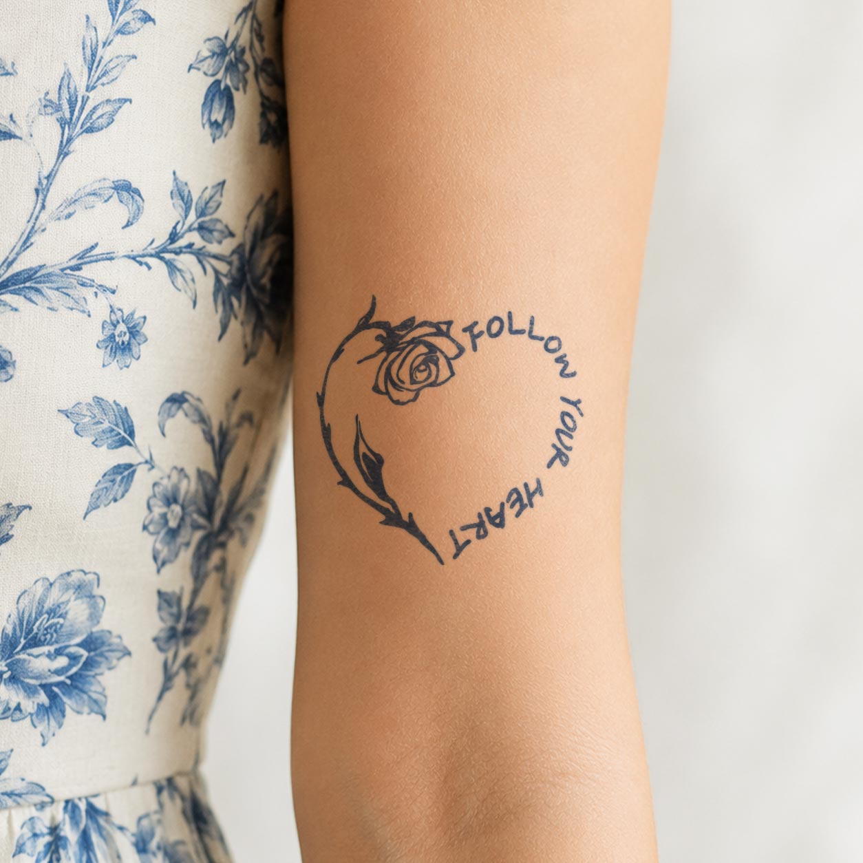 Semi-permanent tattoo featuring a rose and the words “Follow Your Heart” arranged in a circular design on the forearm.