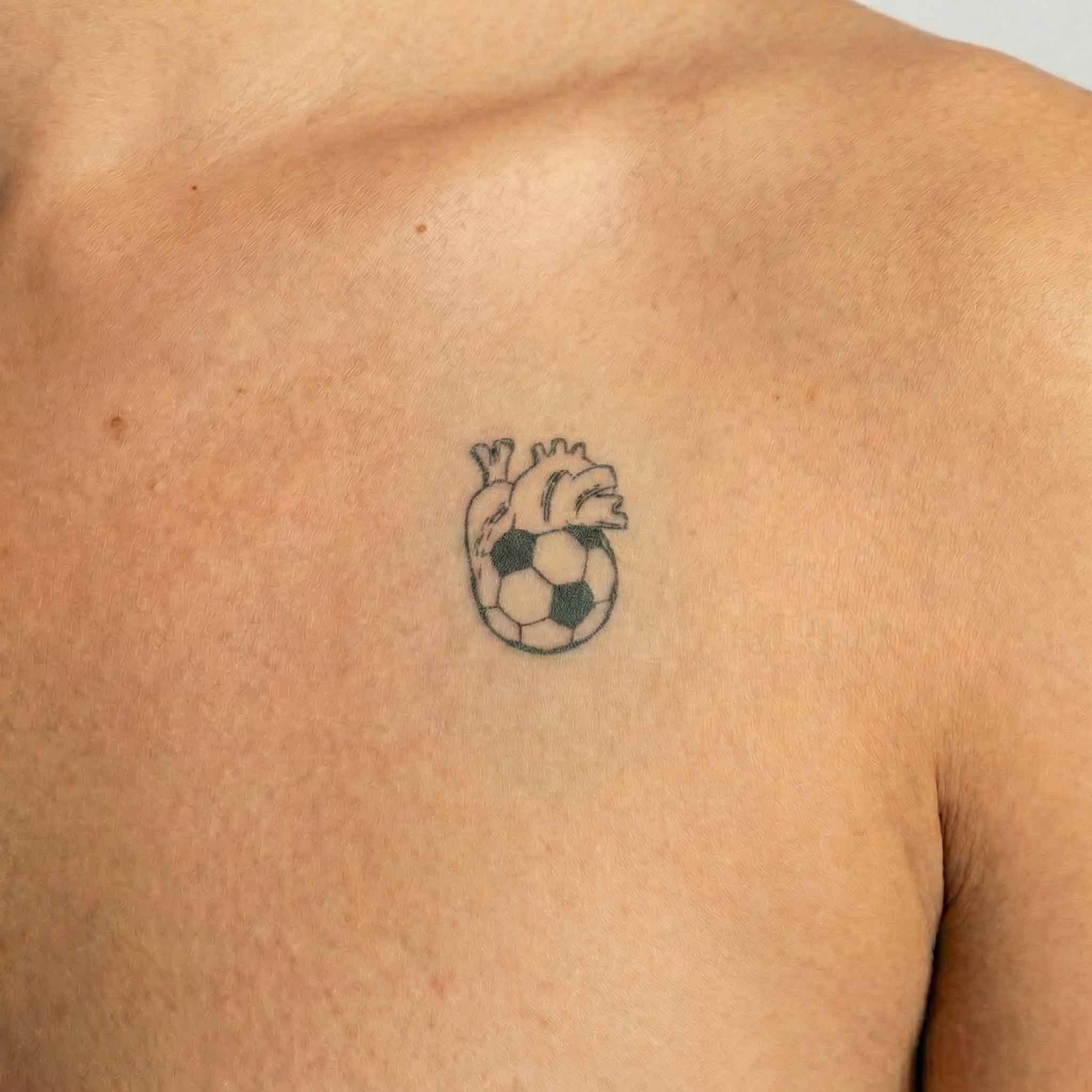 Minimal soccer heart temp tattoo worn on the clavicle with athletic symbolic design