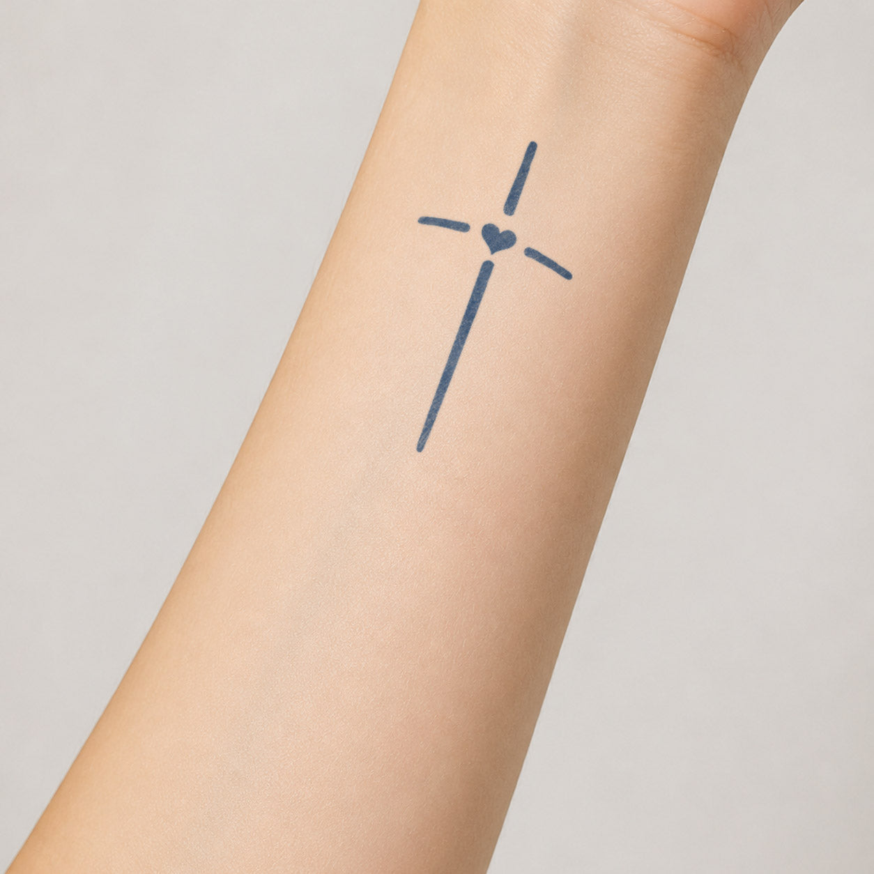 Temporary forearm tattoos featuring a simple cross with a small solid heart at its center.
