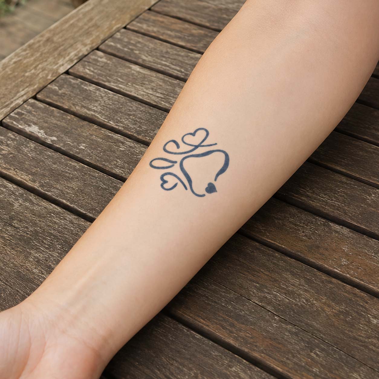 Small temporary tattoos featuring a dog paw created from heart-shaped pads on the inner forearm.