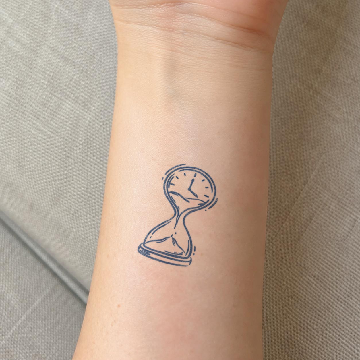 Temporary wrist tattoos featuring a surreal melting hourglass with a small clock face.

