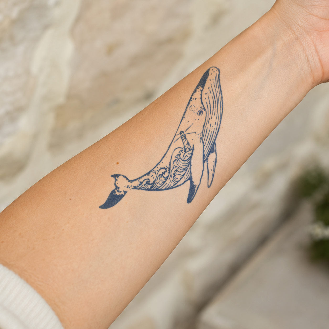 Temporary forearm tattoos featuring a detailed humpback whale with flowing ocean-inspired linework inside its body.
