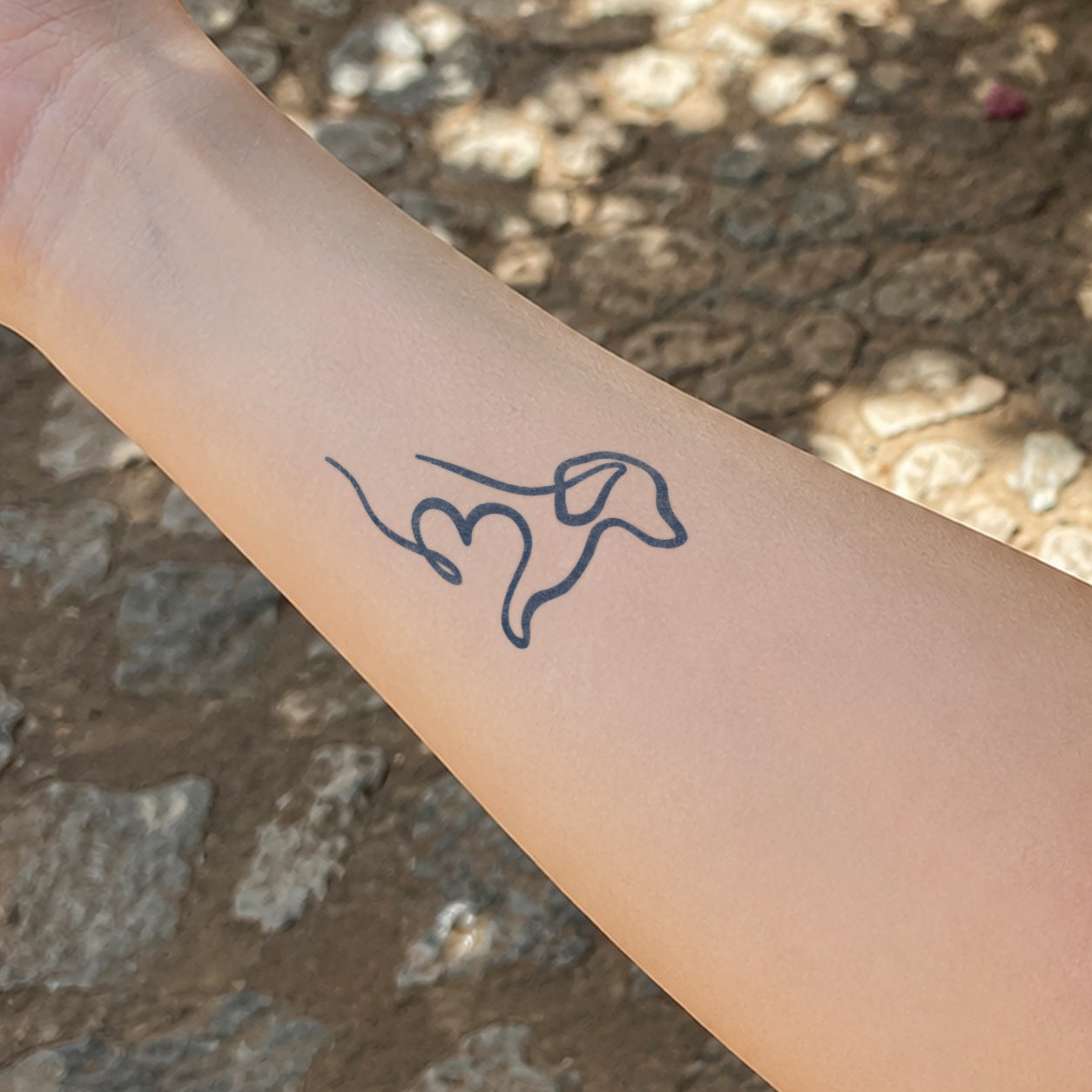 Semi permanent tattoo featuring a simple one-line dog with a heart-shaped detail on the forearm.