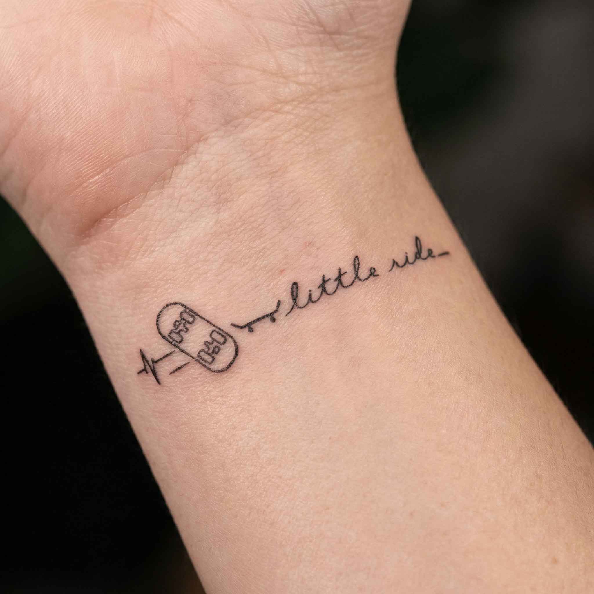 Skateboard fine line temp tattoos worn on wrist