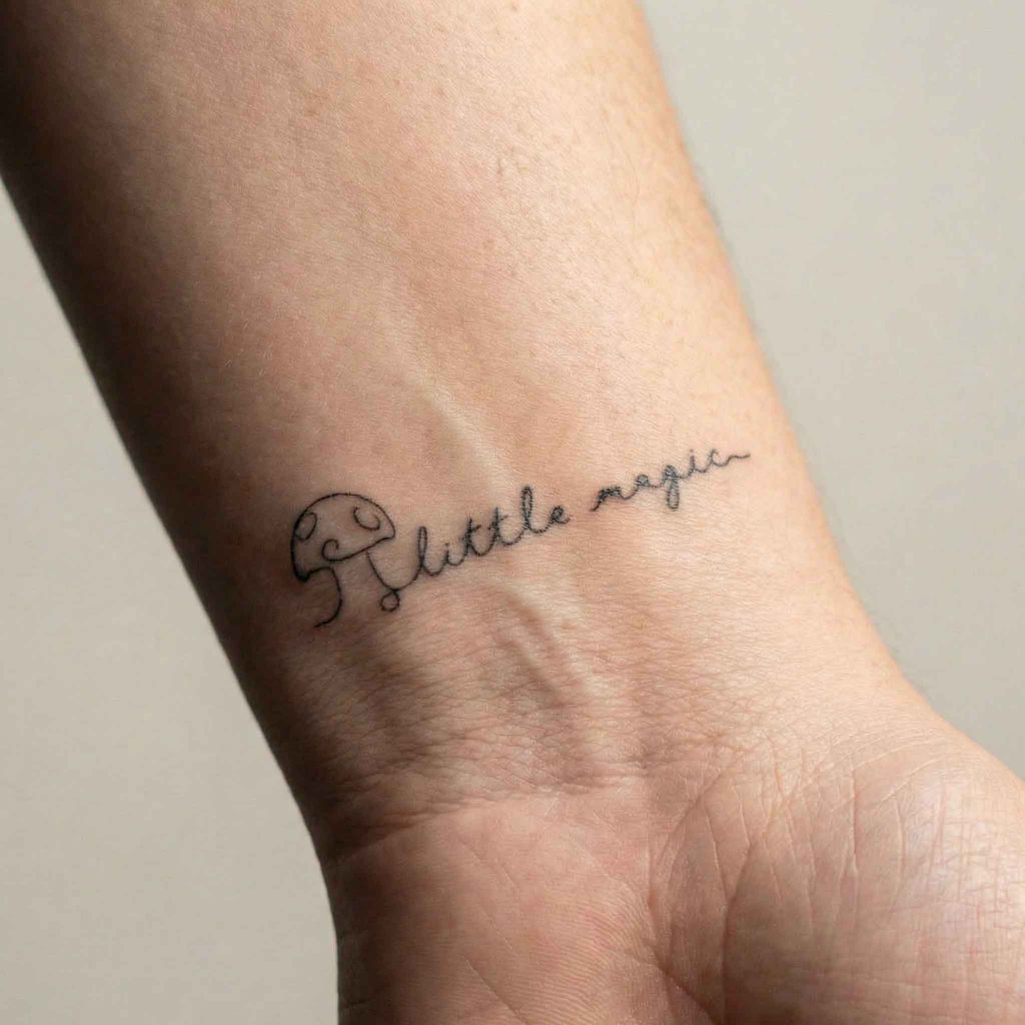 Tiny handwritten quote tattoos with mushroom designs worn on clavicle