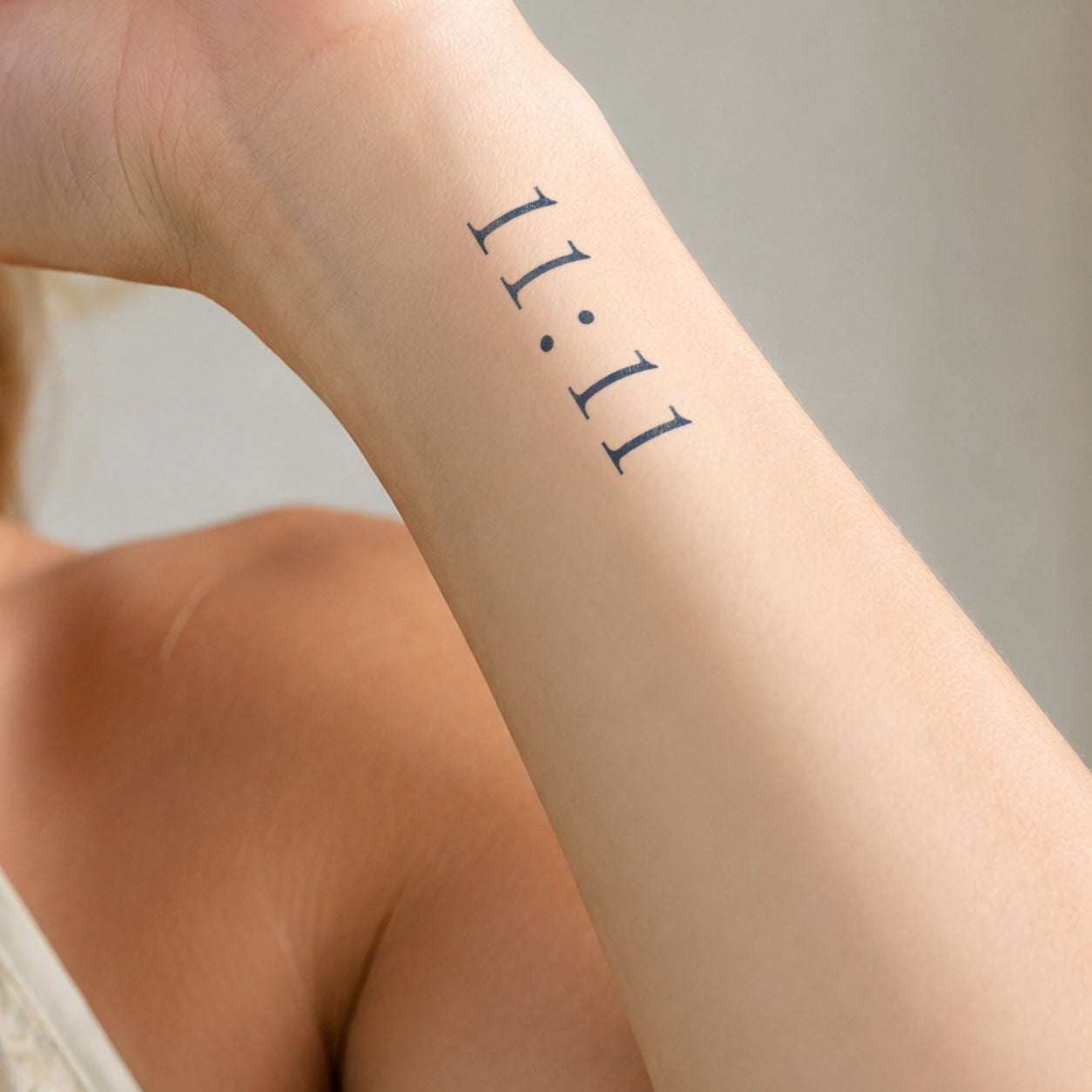 Minimal 11:11 temporary tattoo featuring clean black numbers and dot separators on the inner wrist, creating a simple meaningful design with a modern aesthetic