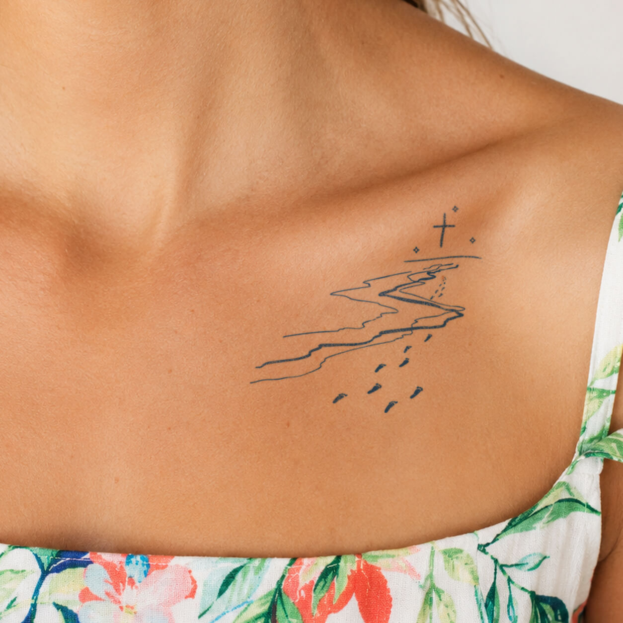 Minimal coastal landscape temporary tattoo featuring abstract ocean waves, shoreline lines, and small stars on the upper back with a delicate nature-inspired design