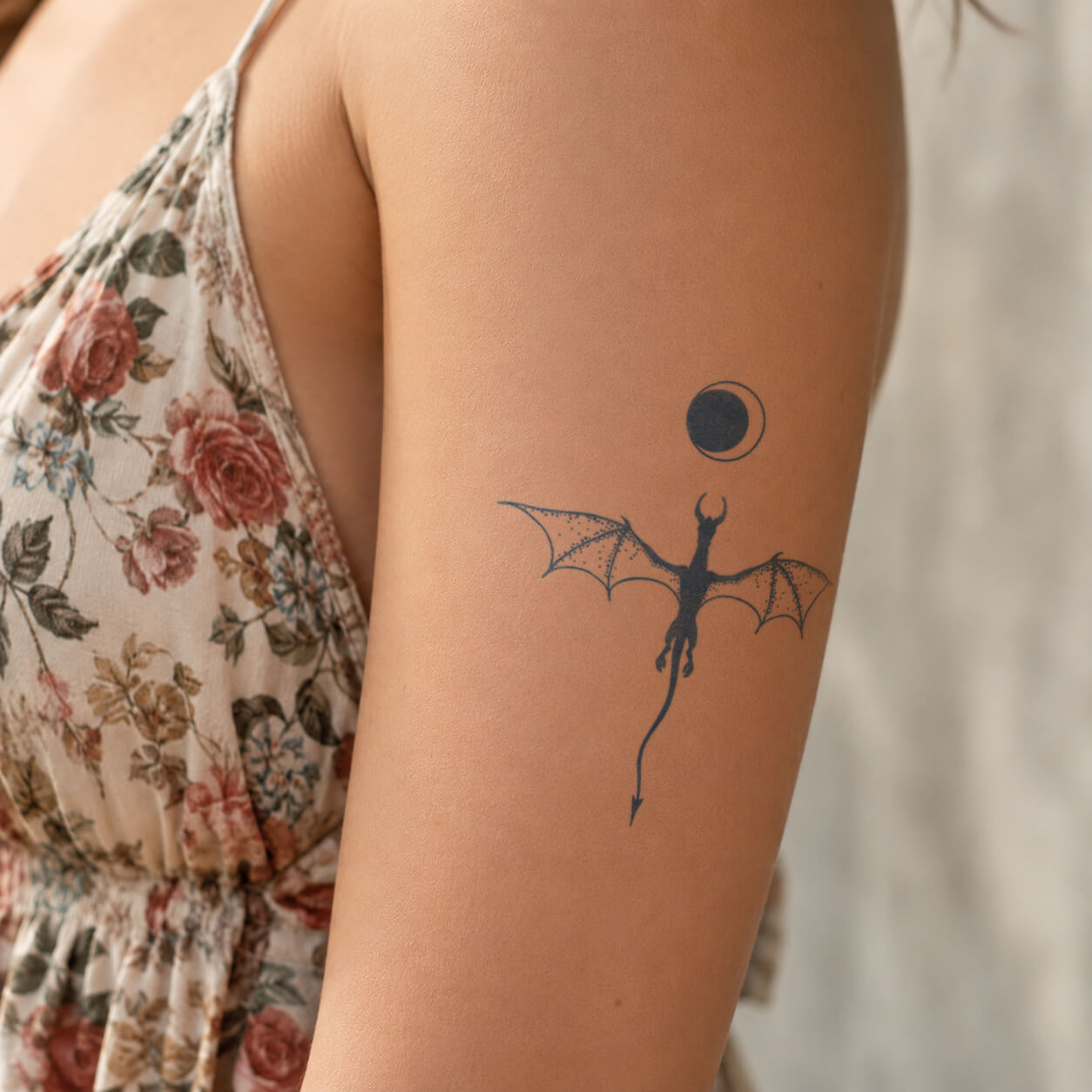 Small flying dragon silhouette with moon detail placed on the upper arm, featuring a fantasy-inspired dragon temporary tattoo design with clean lines and a minimalist style.