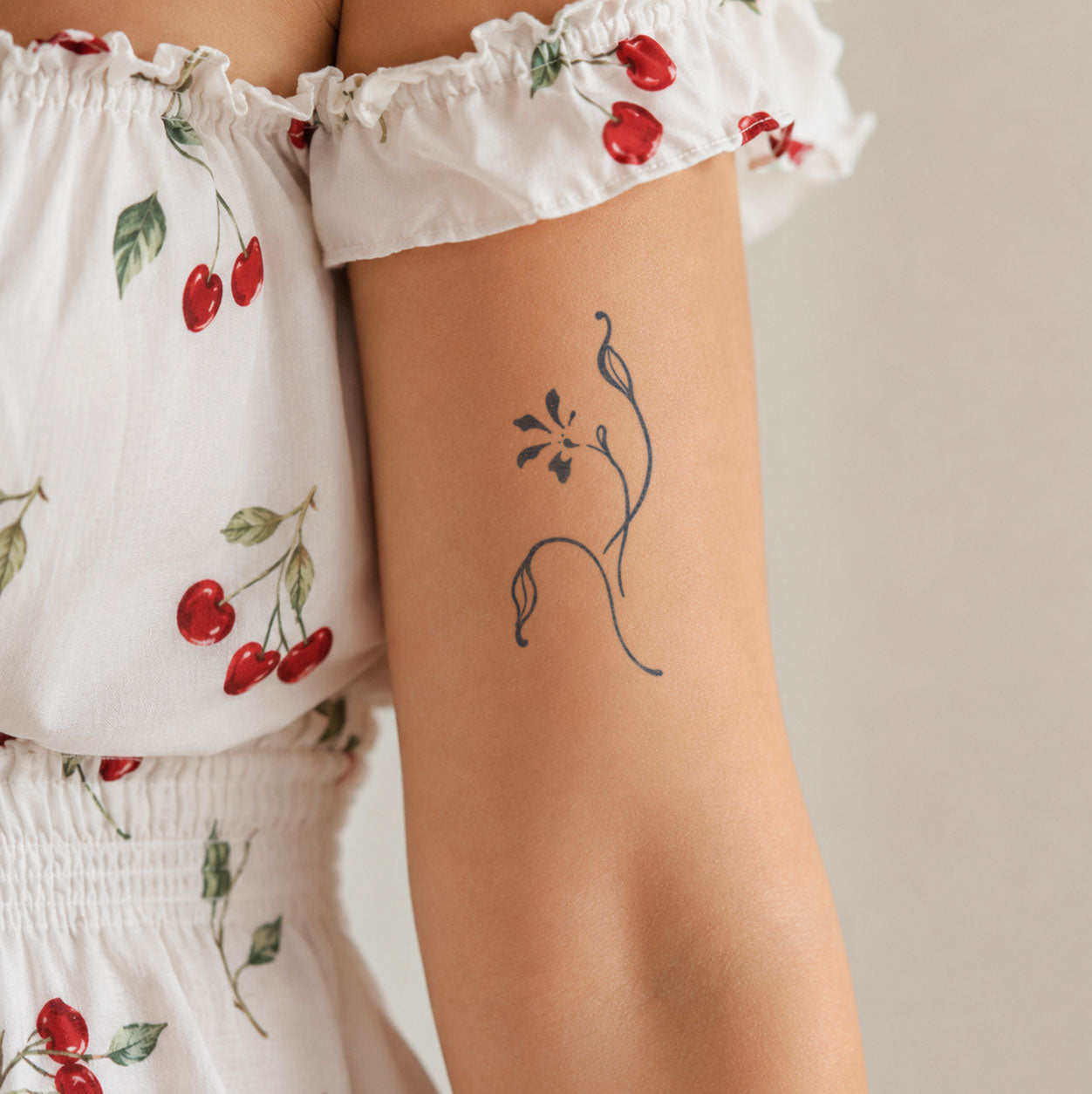 Temporary arm tattoos featuring an abstract open flower, a curved stem, and a closed flower bud.