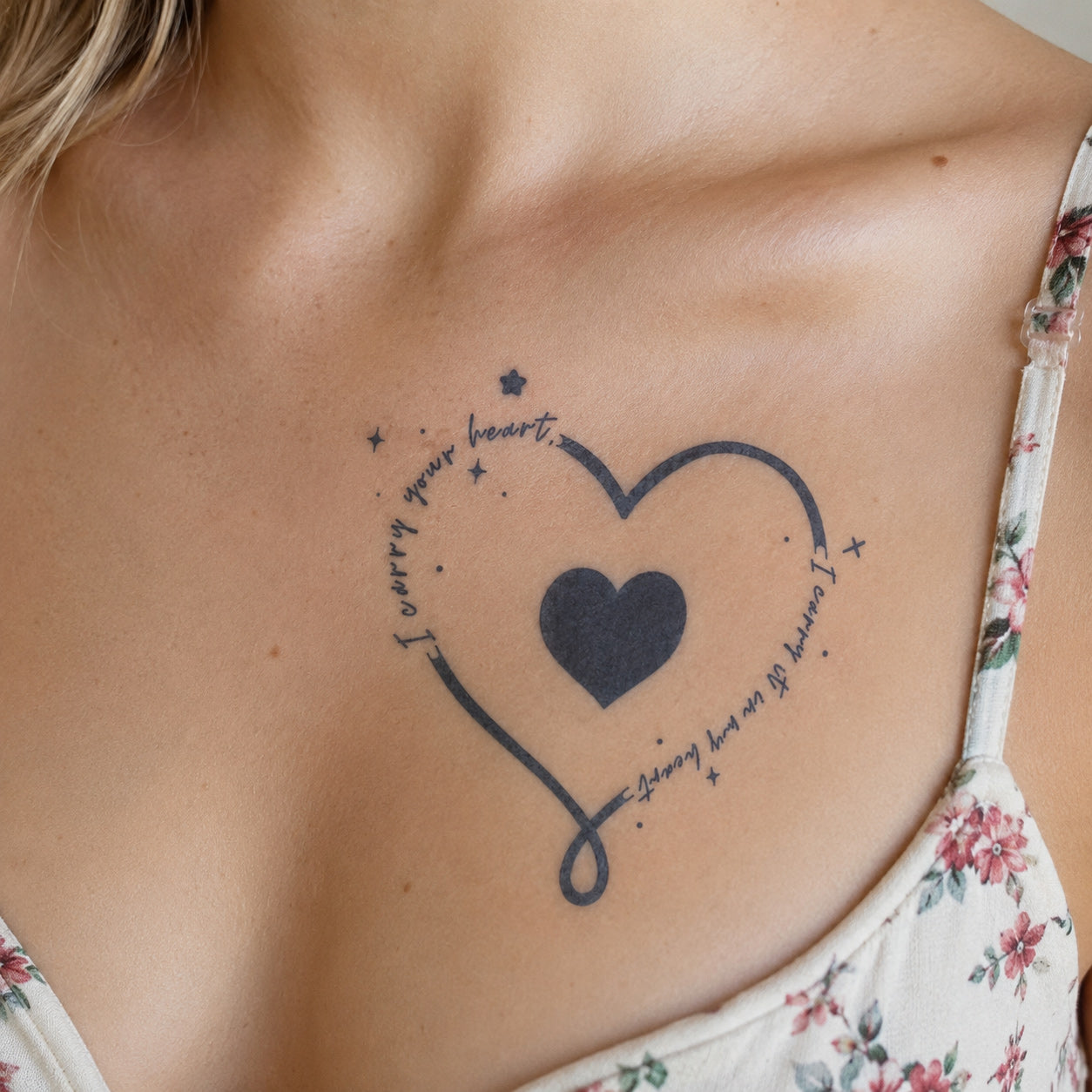 Minimal heart outline tattoo with handwritten quote lettering placed on a woman’s chest, showcasing a delicate heart temporary tattoo design.