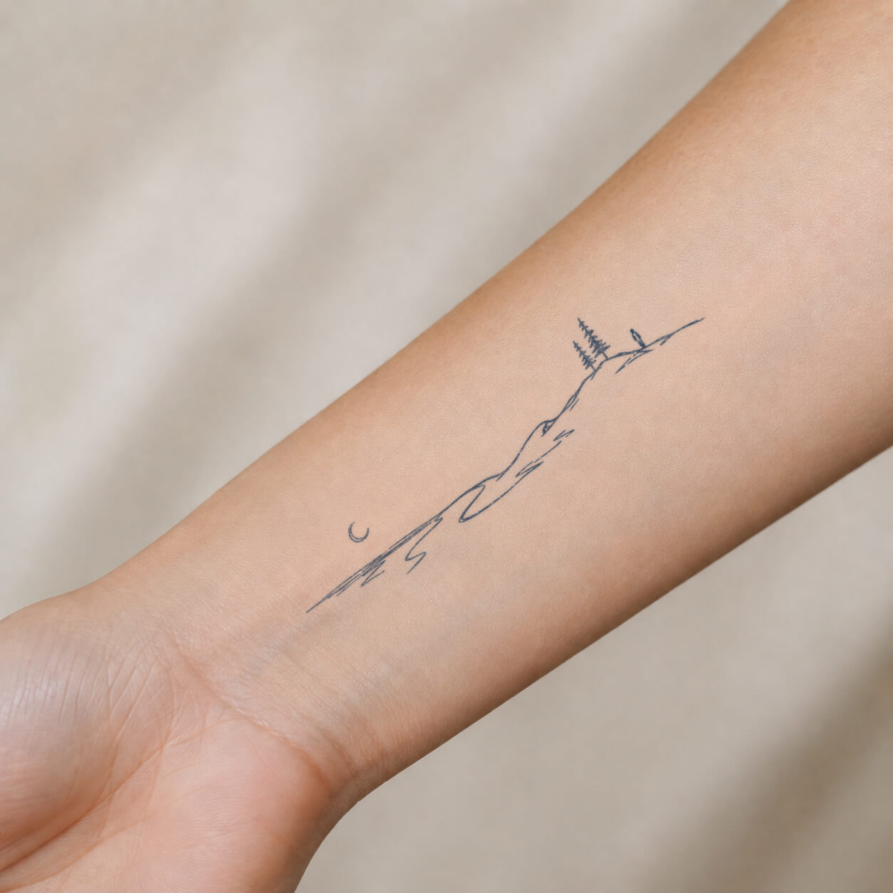Small mountain landscape temp tattoo with moon and nature details placed on the inner wrist, featuring a delicate nature temporary tattoo design.