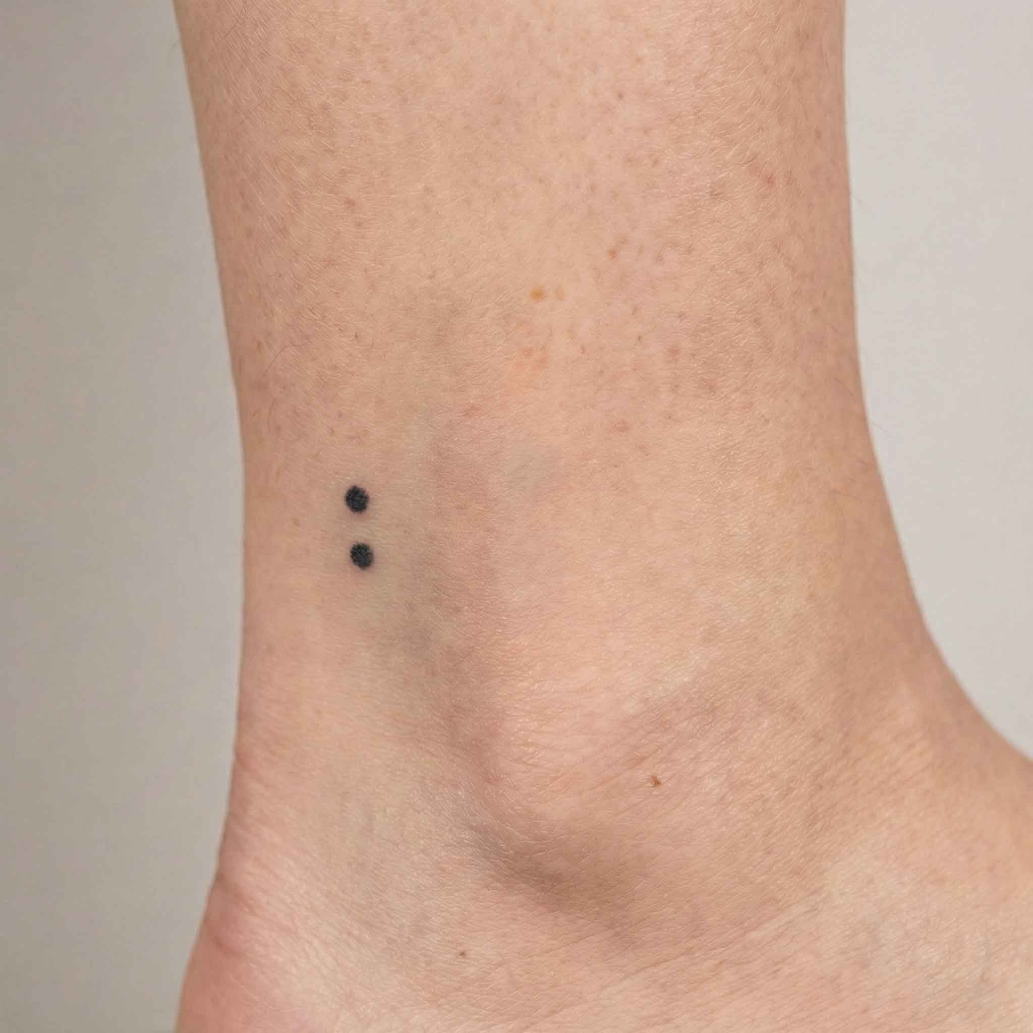 Minimal punctuation tattoo worn on the ankle