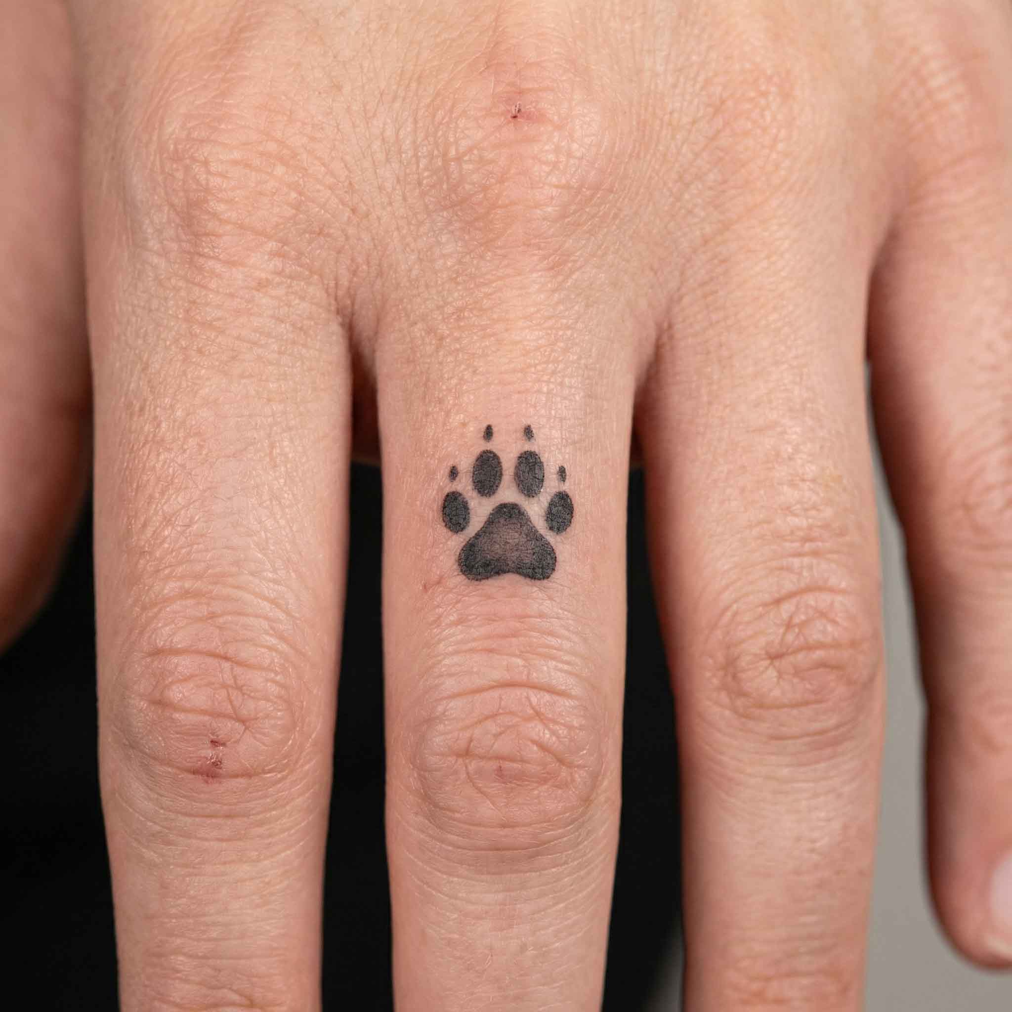 Small paw print animal fake tattoo worn on fingerwith simple pet lover style