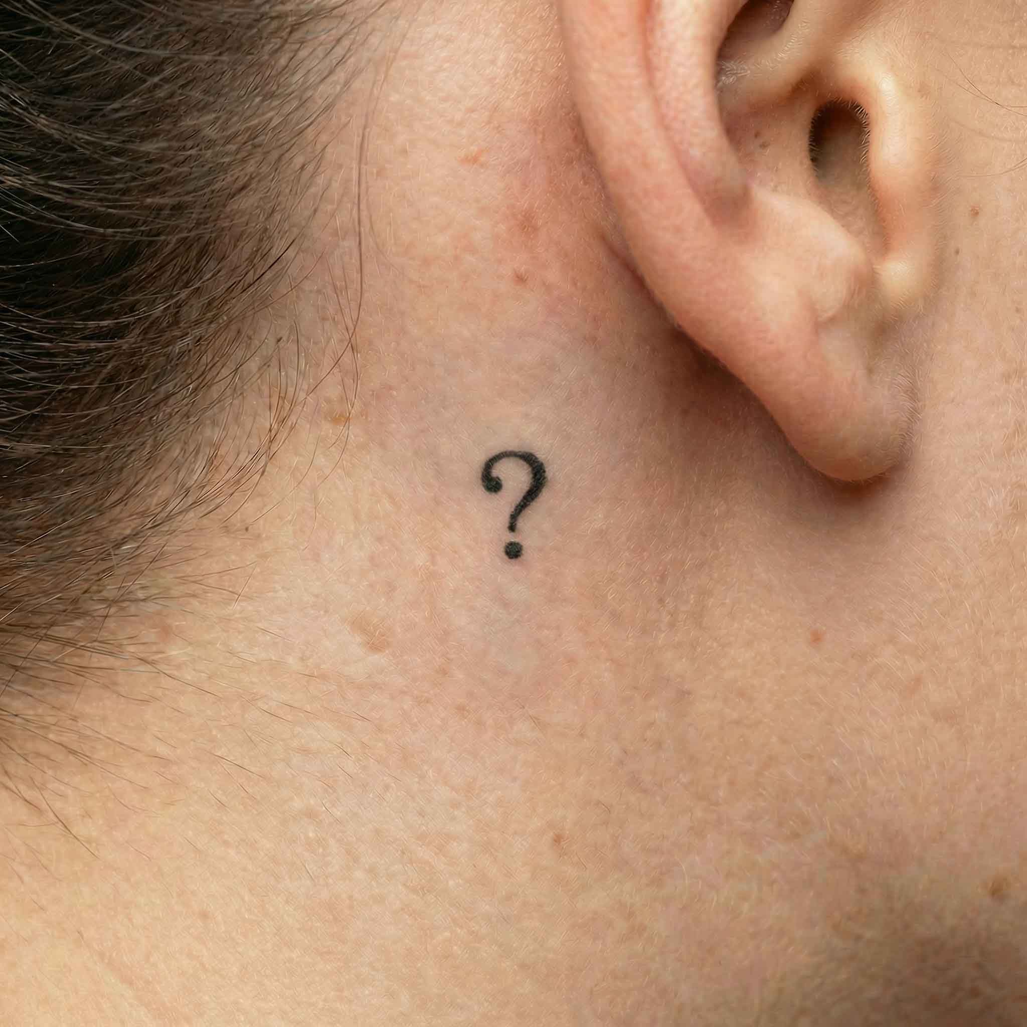 Minimal punctuation tattoo worn behind the ear
