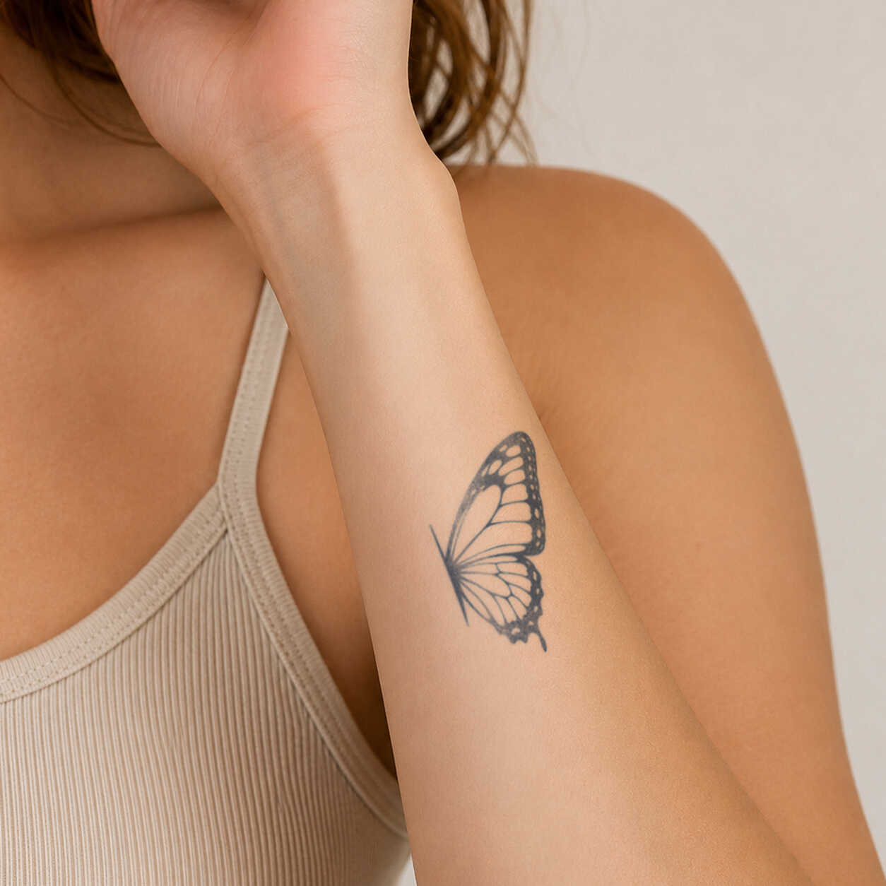 Minimalist butterfly wing temporary tattoo on forearm