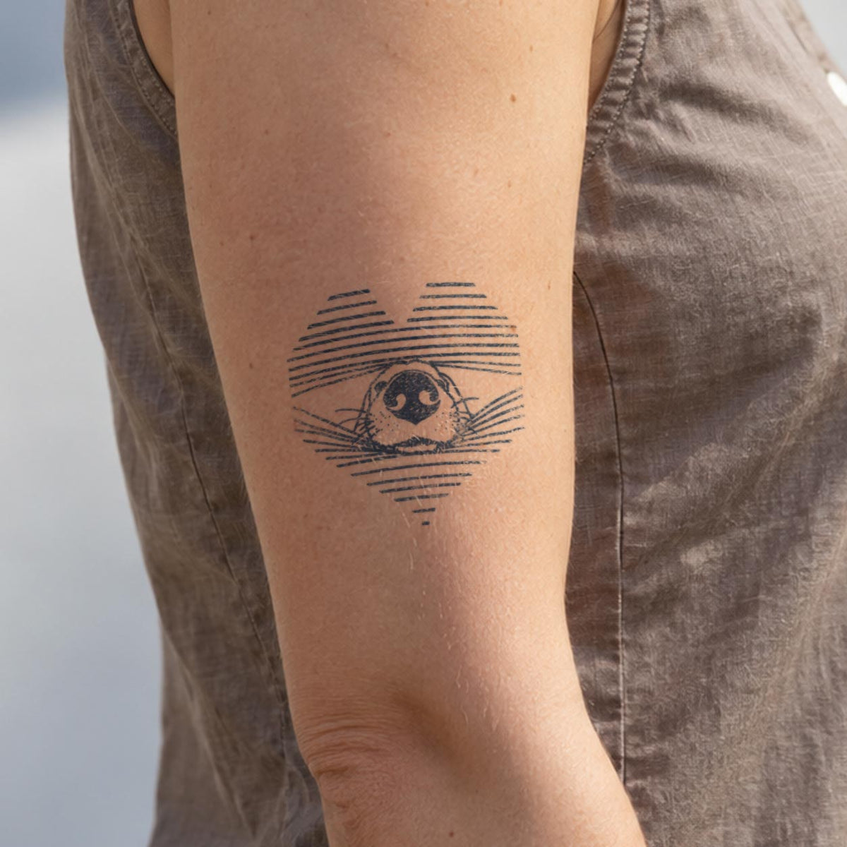 Aesthetic temporary tattoos featuring a dog nose centered inside a striped heart design in blue-black ink on the upper arm.