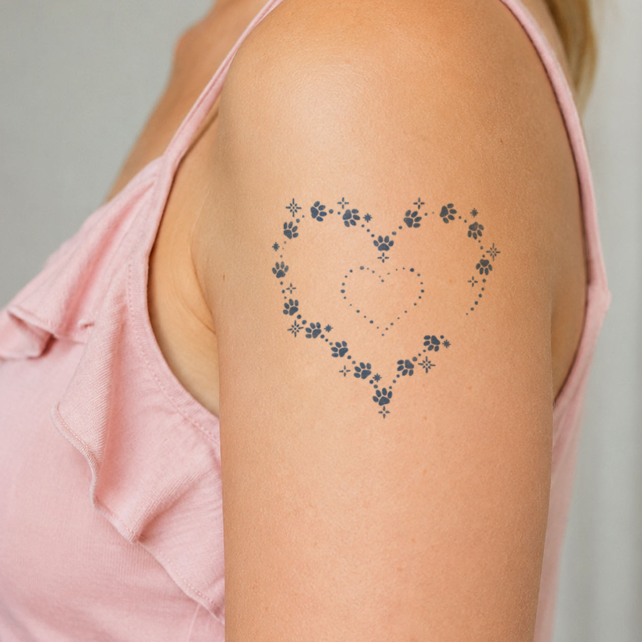 Temporary shoulder tattoos featuring paw prints, dotted lines, and tiny stars arranged into layered heart outlines.