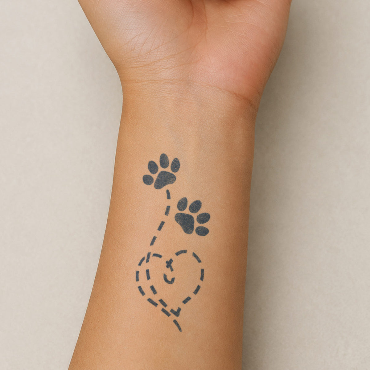 Aesthetic temporary tattoos featuring two paw prints connected by a playful dotted heart trail in blue-black ink.