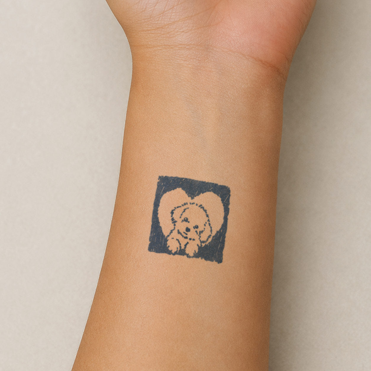 Small semi permanent tattoo featuring a cute puppy framed inside a heart-shaped black design on the wrist.
