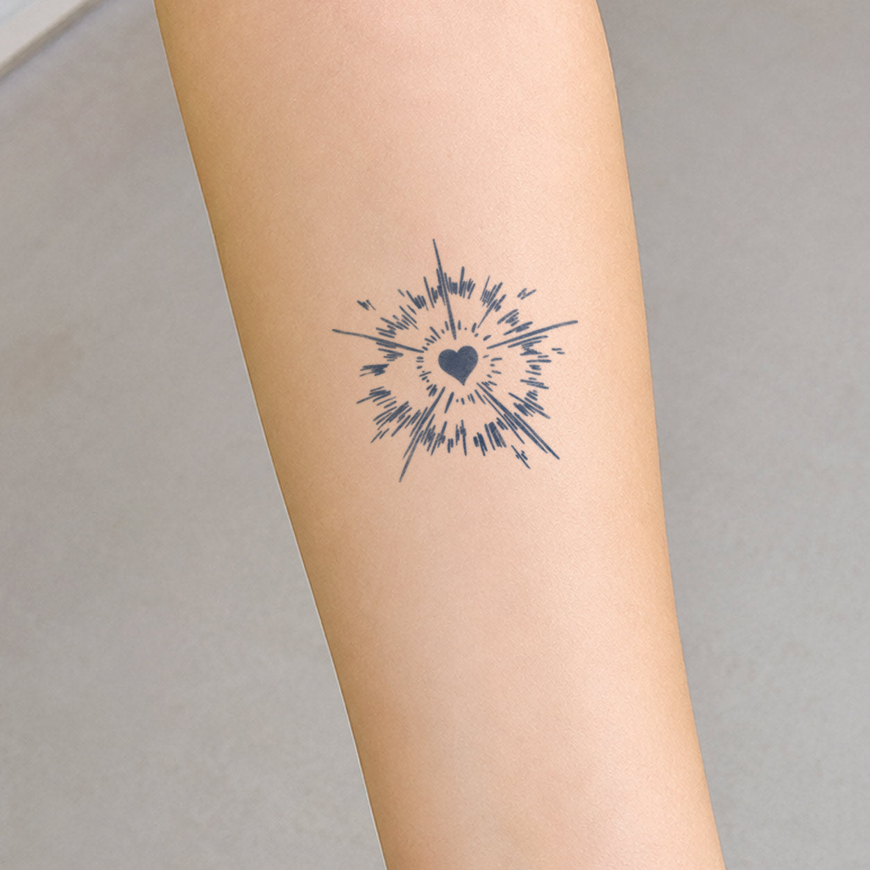 Temporary forearm tattoos featuring a solid heart surrounded by a hand-drawn burst of radiating lines.
