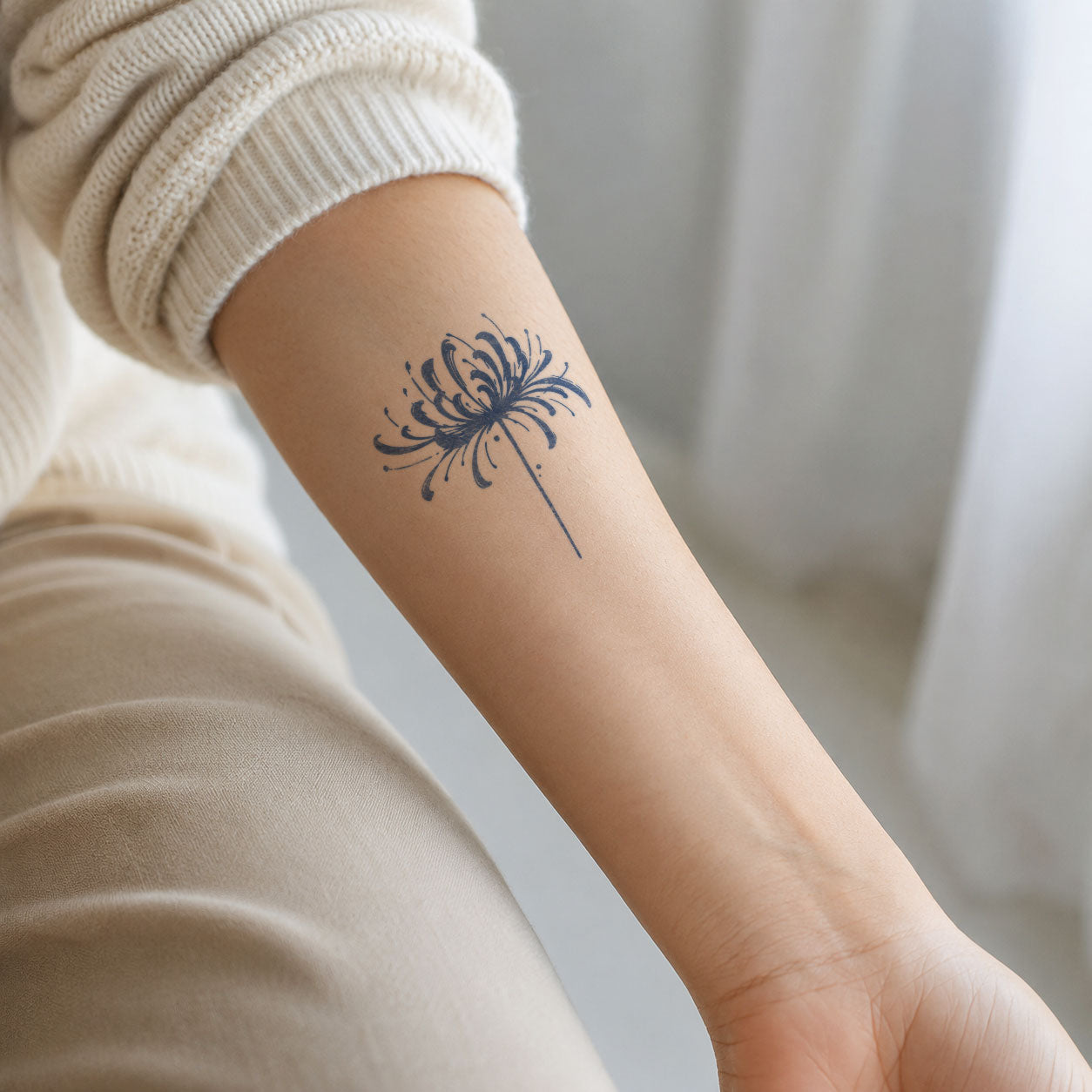 Flower temporary tattoo featuring a delicate spider lily with long curling petals on the inner forearm.
