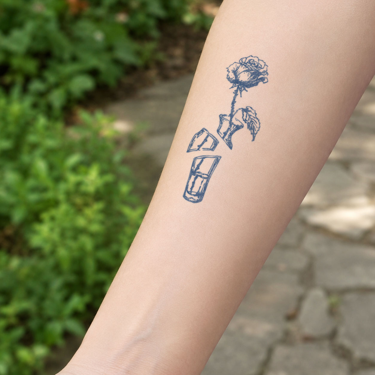 Floral temporary tattoos featuring a blooming rose growing from a cracked glass bottle, with broken glass fragments below.
