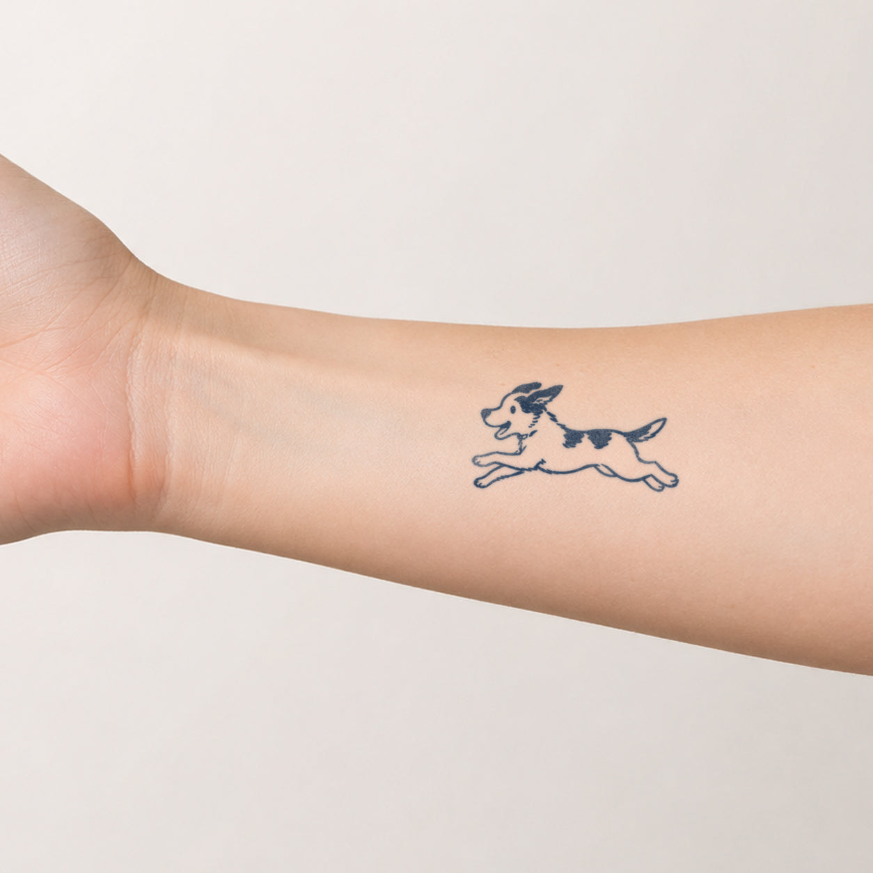Simple running dog outline design placed on the forearm, featuring a playful dog temporary tattoo with clean lines and a minimal pet-inspired style.