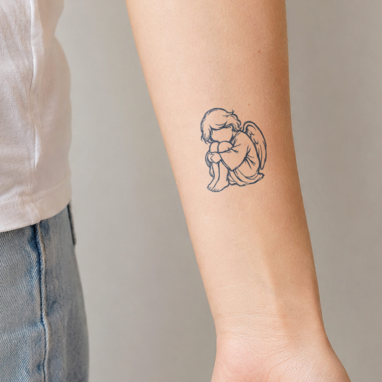 Delicate fine line tattoo featuring a small sleeping angel child sitting with folded arms and wings. This minimalist temporary tattoo design creates a soft and meaningful look with a peaceful, innocent style.