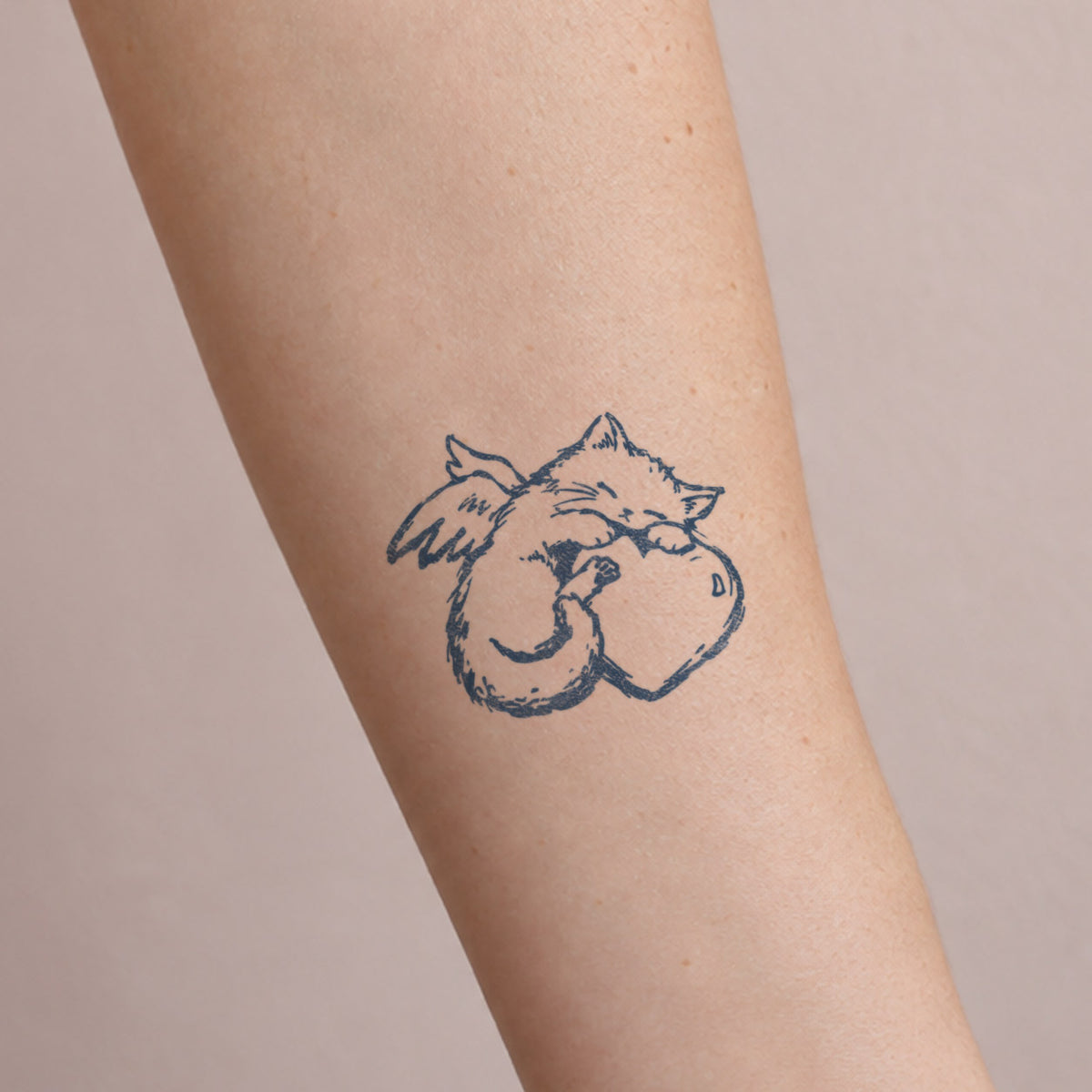 Temporary forearm tattoos featuring a cute cat hugging a heart in a soft blue-black hand-drawn style.