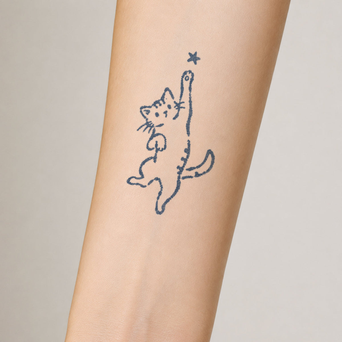 Temporary forearm tattoos featuring a cute minimalist cat reaching toward a small star in a blue-black line art style.