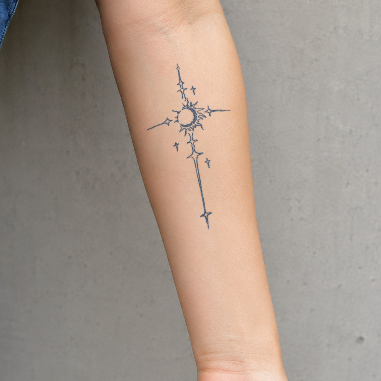 Temporary forearm tattoos featuring a cross with a radiant sun at the center and tiny star details.
