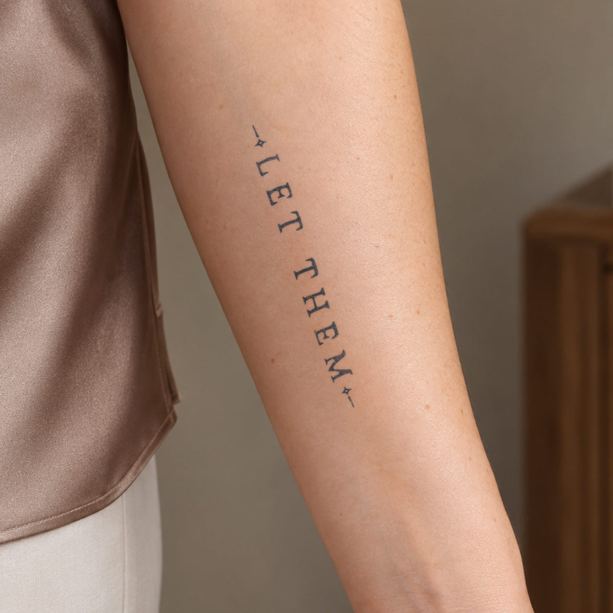 Temporary forearm tattoos featuring a minimalist “LET THEM” word design in dark blue-black ink on the inner arm.