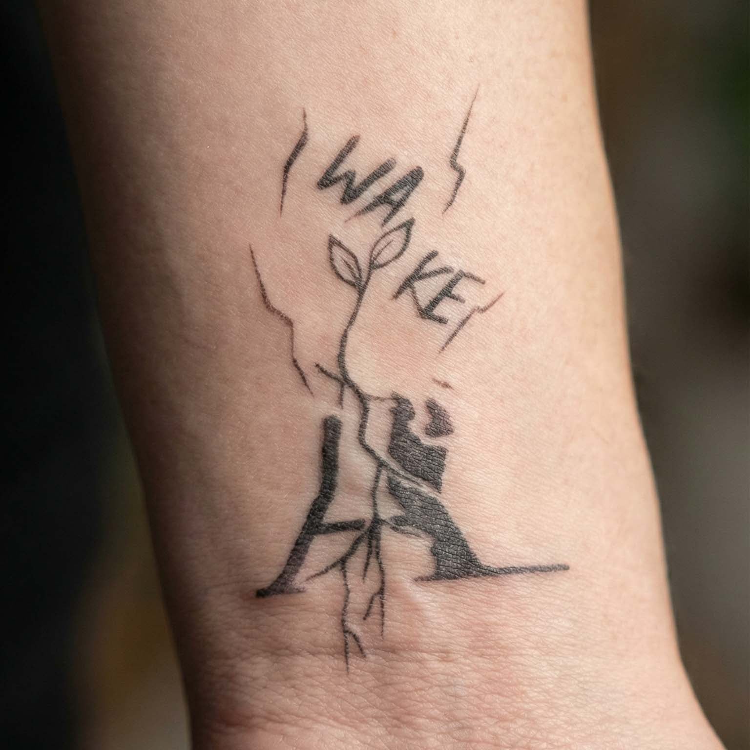 Awake temporary tattoo with sprout breaking through soil on wrist